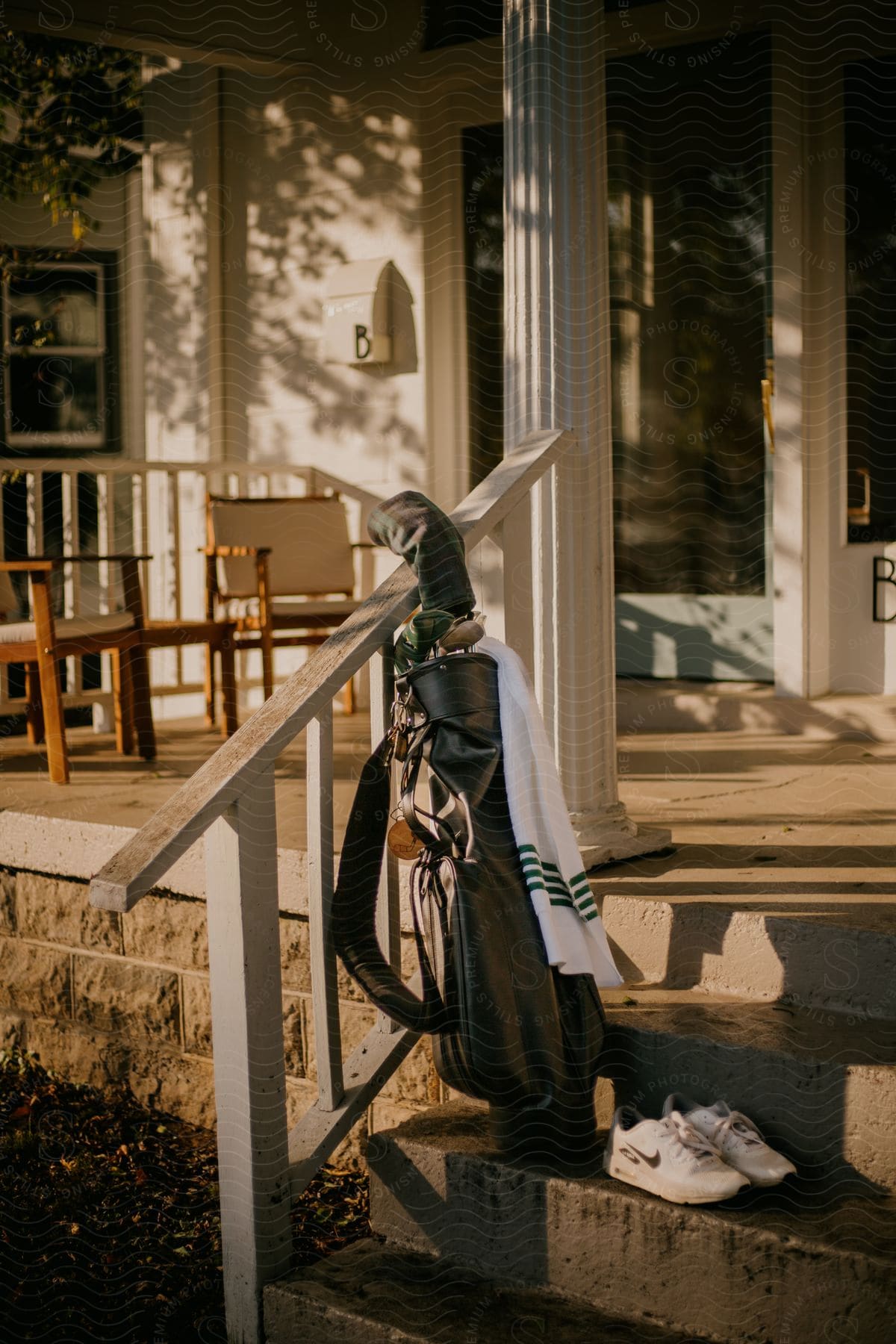 Golf bag holding golf clubs rests against rail on house steps.