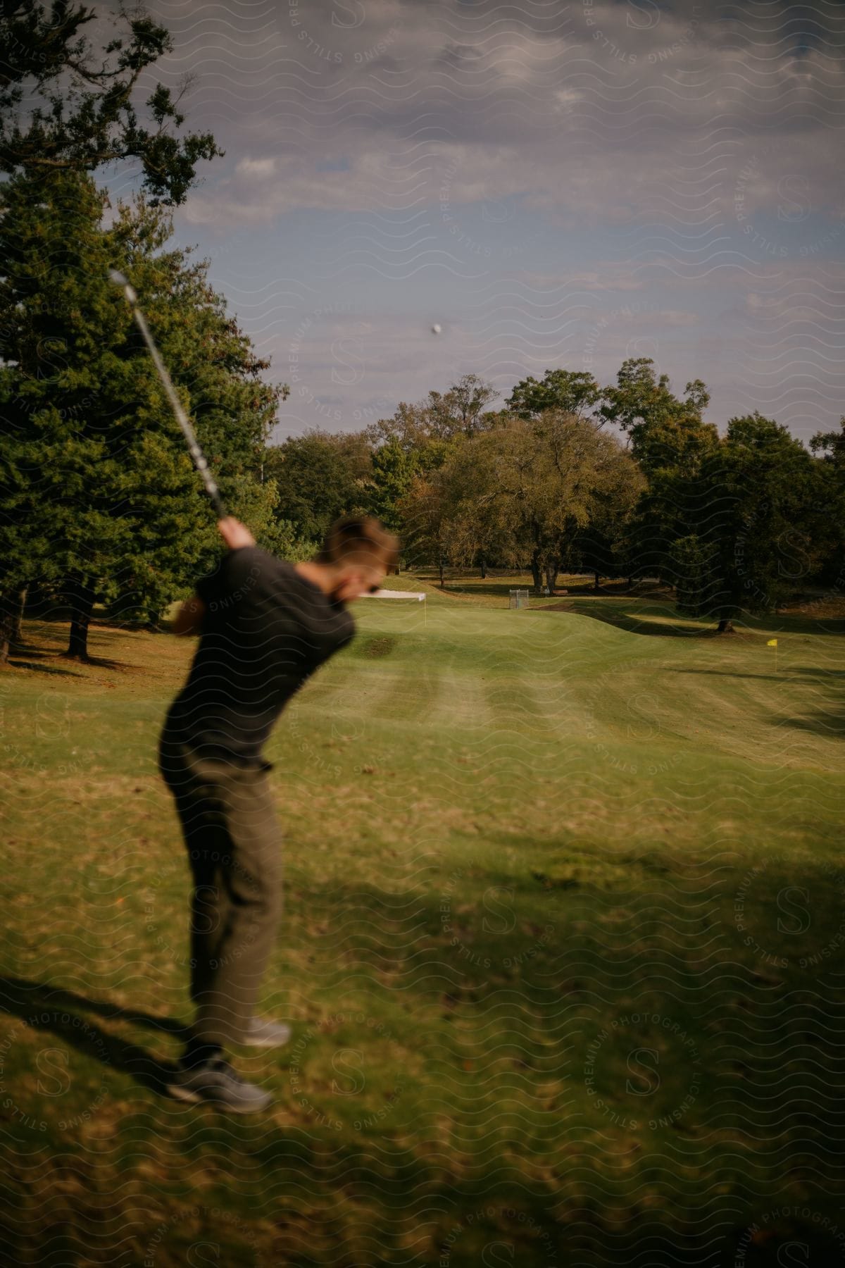 Man teeing off and driving a golf ball on a golf course.