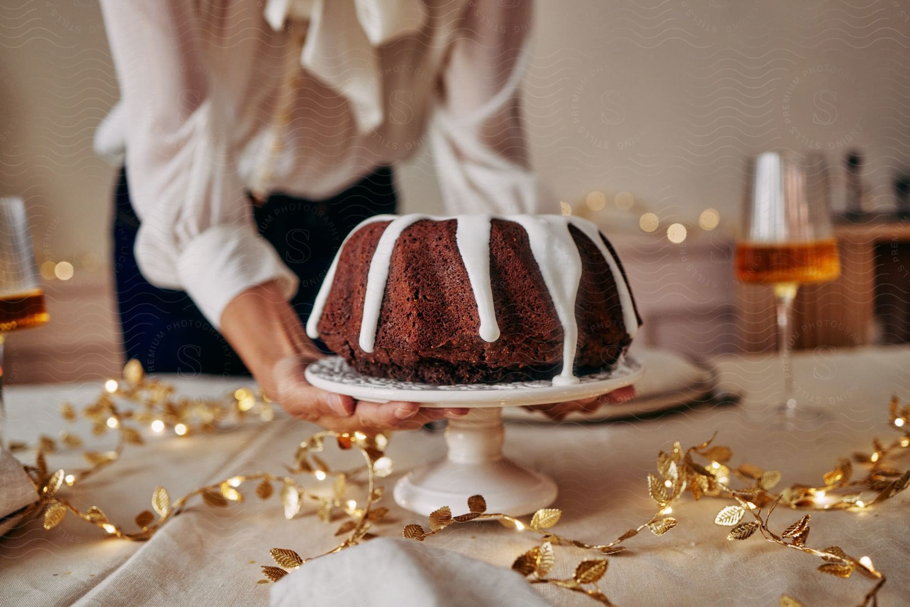 A woman is placing a chocolate bundt cake on a table decorated for a party