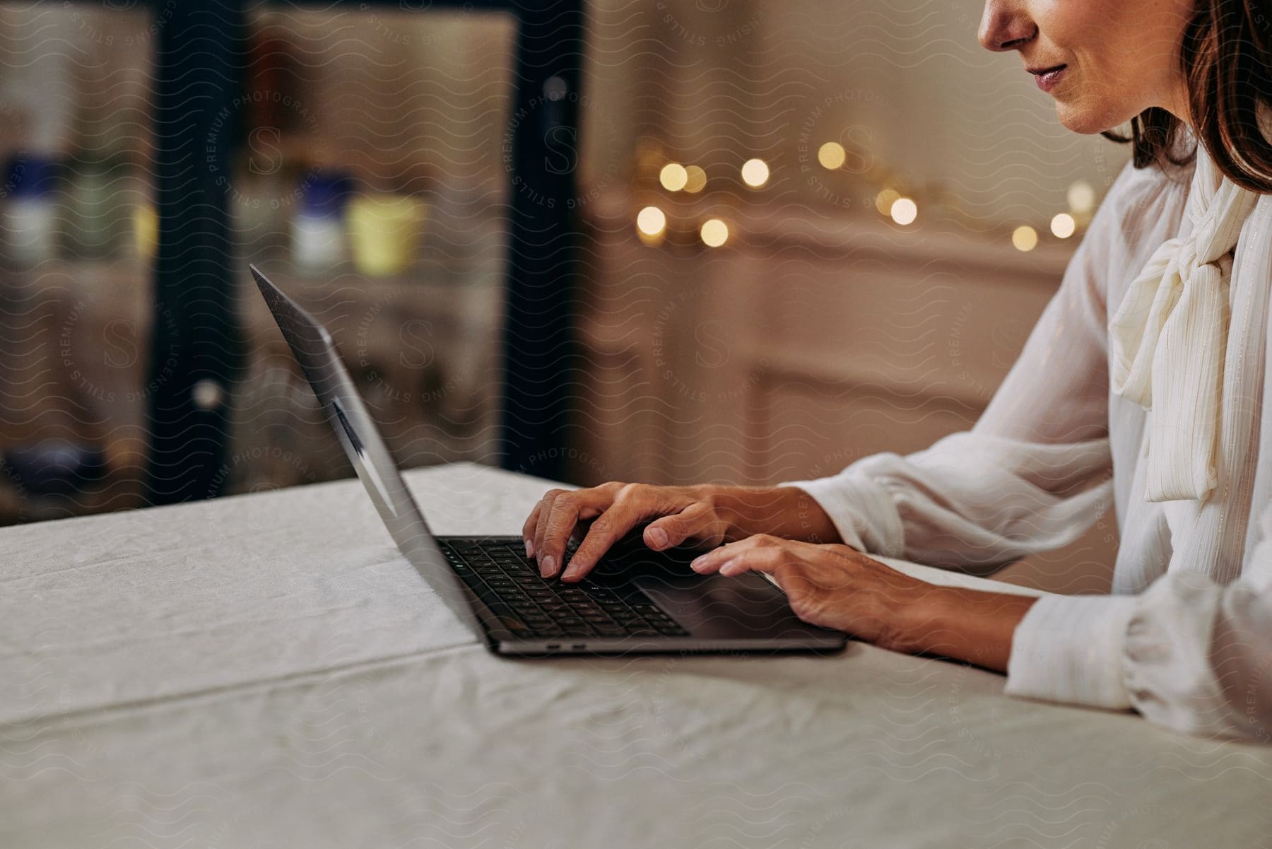 Woman with a white shirt sits at table working on a laptop