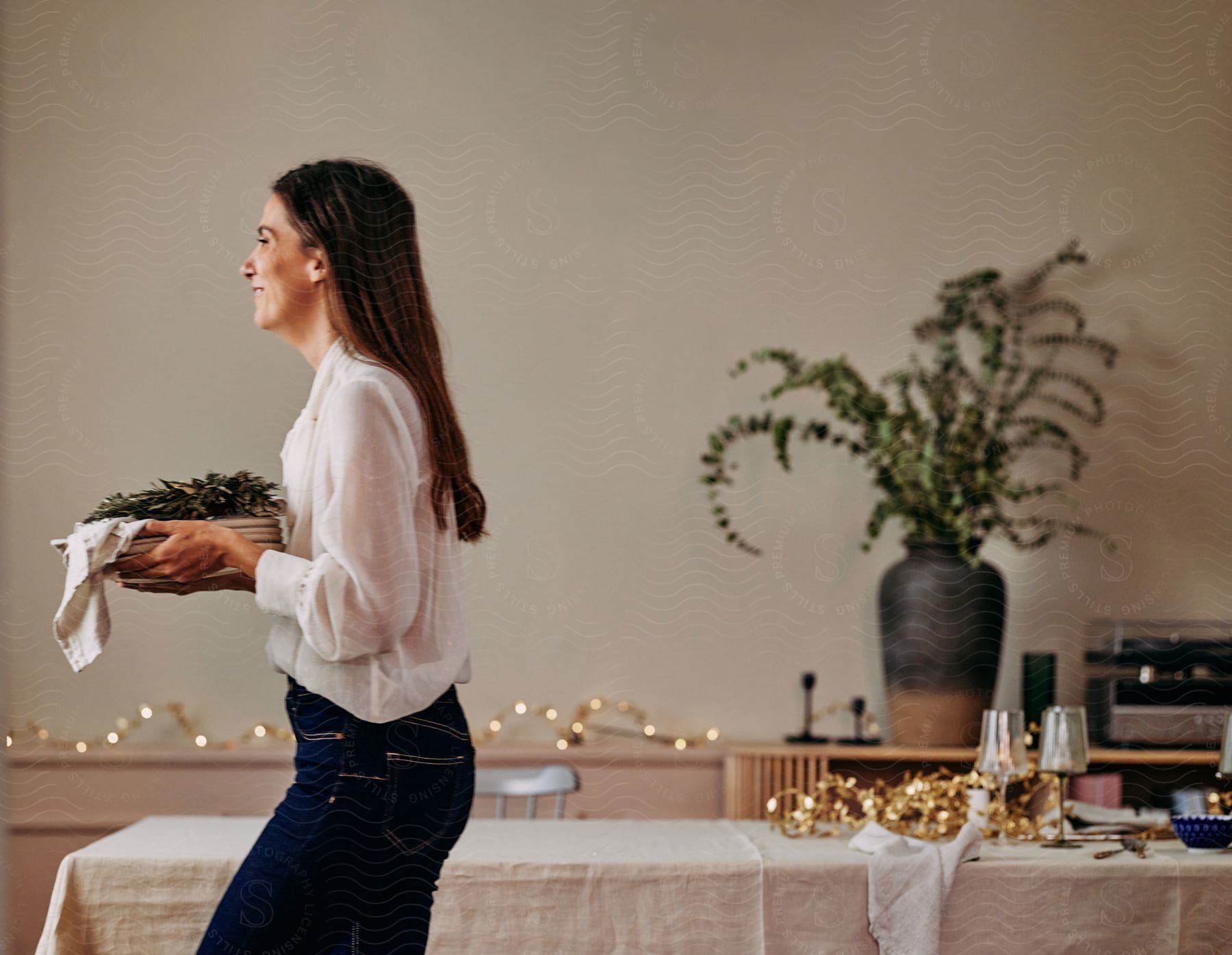 A woman carrying food in a restaurant to a table to serve it.