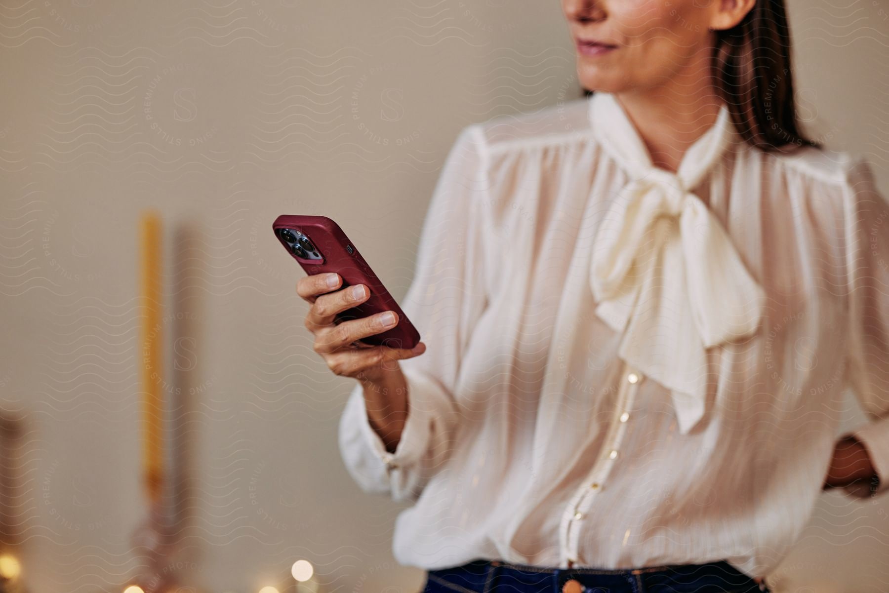 Stock photo of a woman is standing in a room looking at the cell phone in her hand