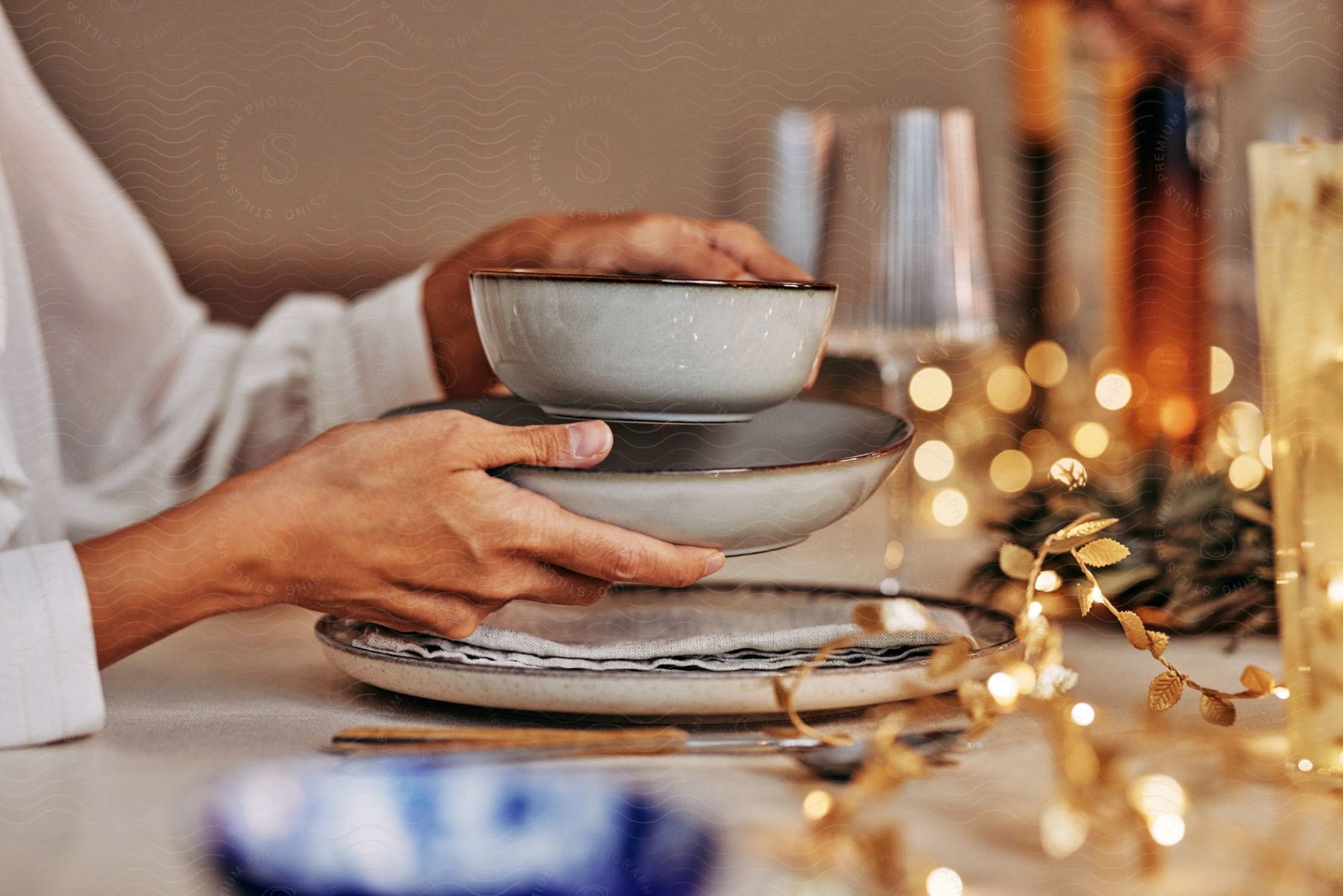 A woman is setting tableware around the decorated fall table.