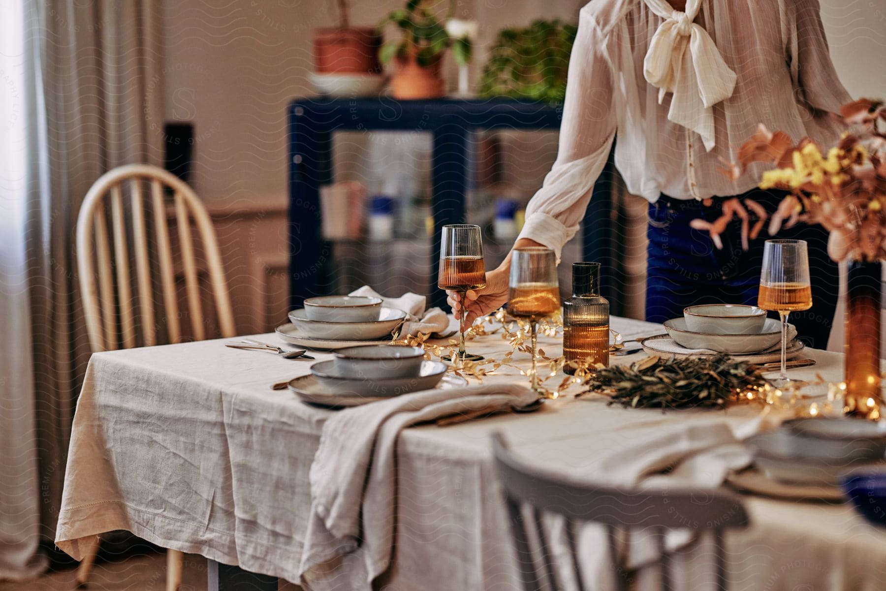 a woman setting up a dining table with meals and glass beverages