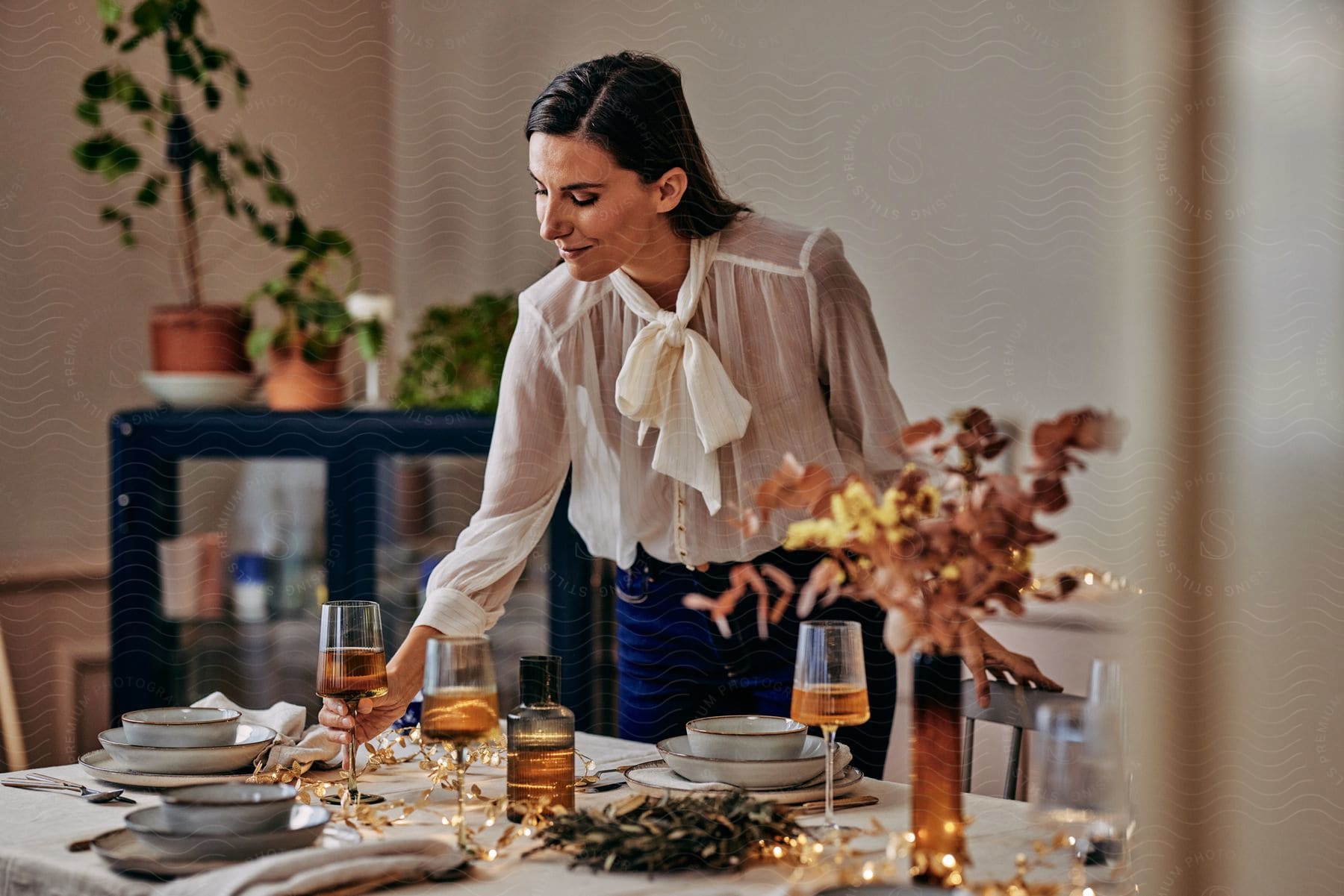 A woman smiling while placing a glass of drink with a beverage on the table.