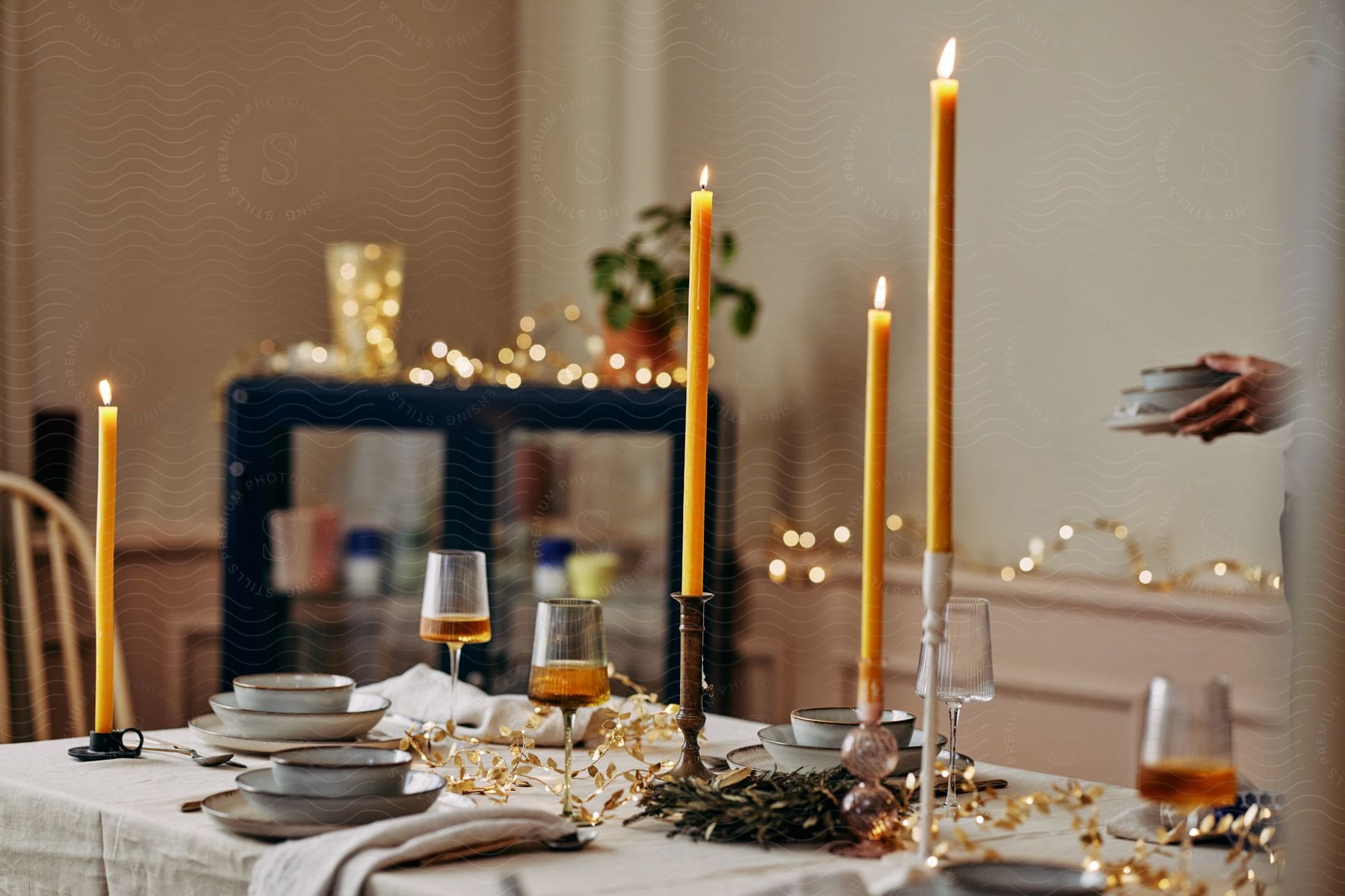 candle setting on a dining table with series of glasses and plates on the table