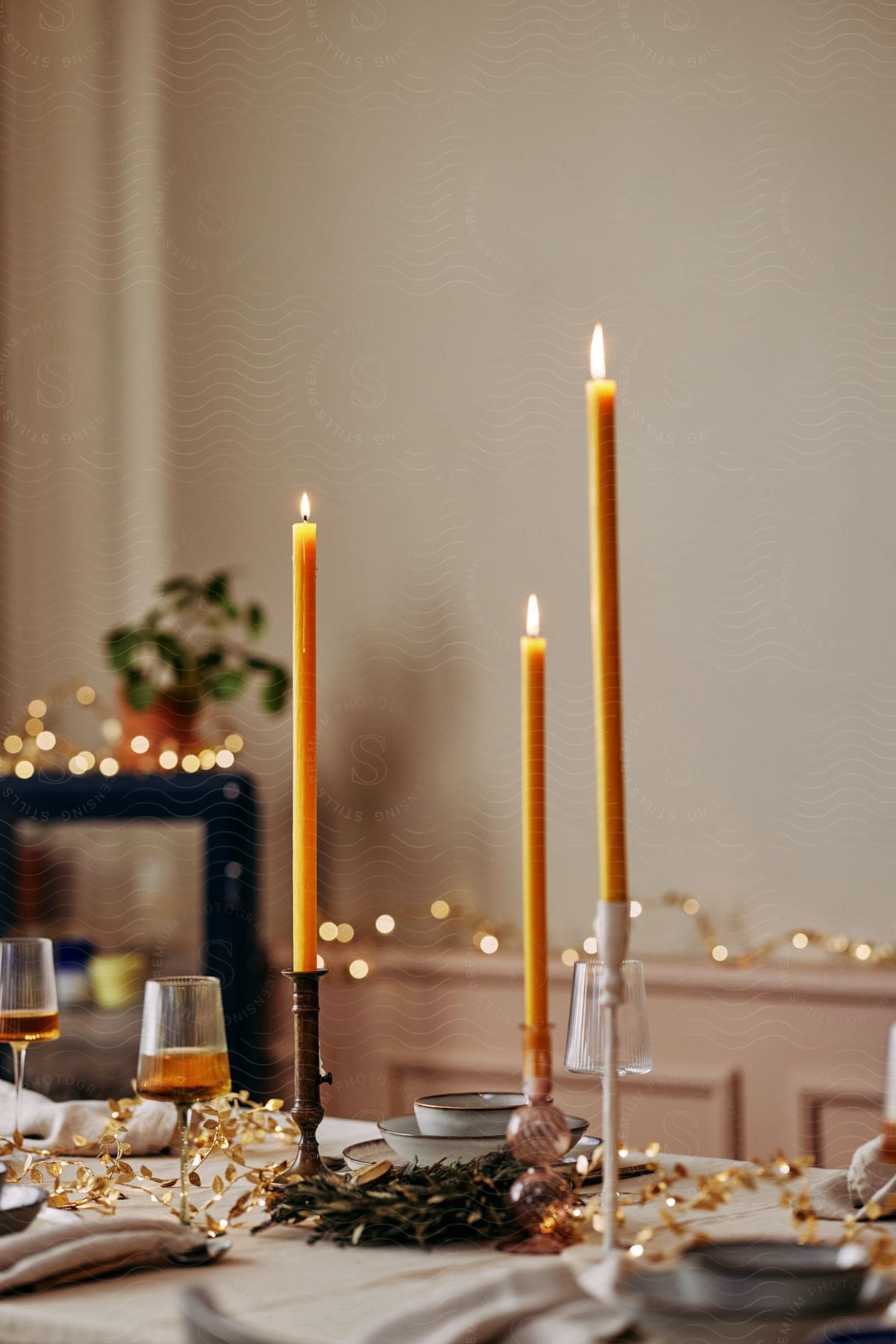 Stock photo of a dining table set up with wine in glasses, plates and candles on candle stands and some deco lights on the background