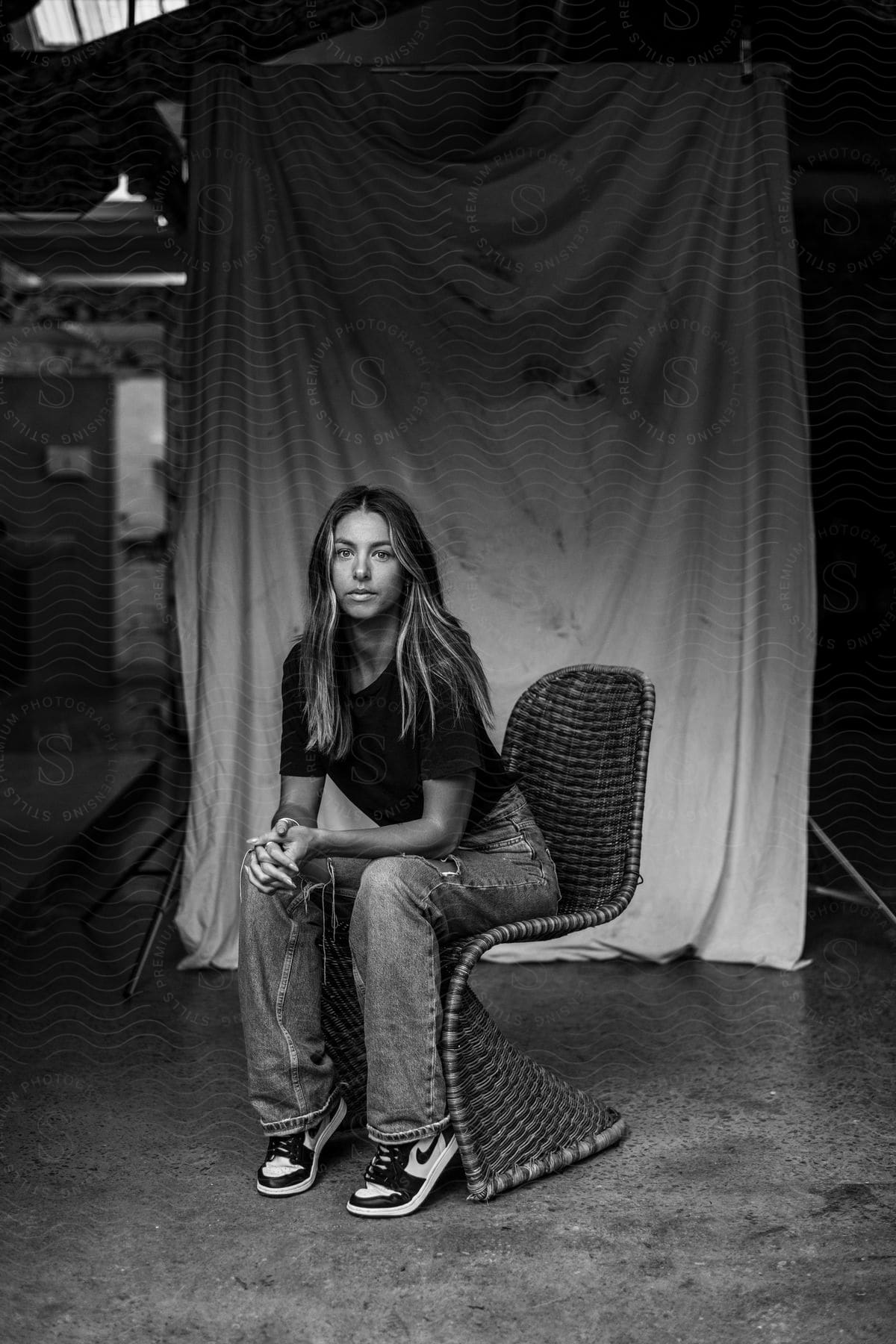 Woman sits on chair in front of canvas backdrop.