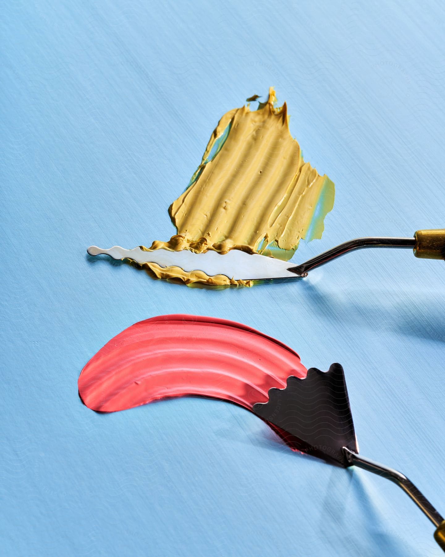 Painting knives spreading paint over a blue surface