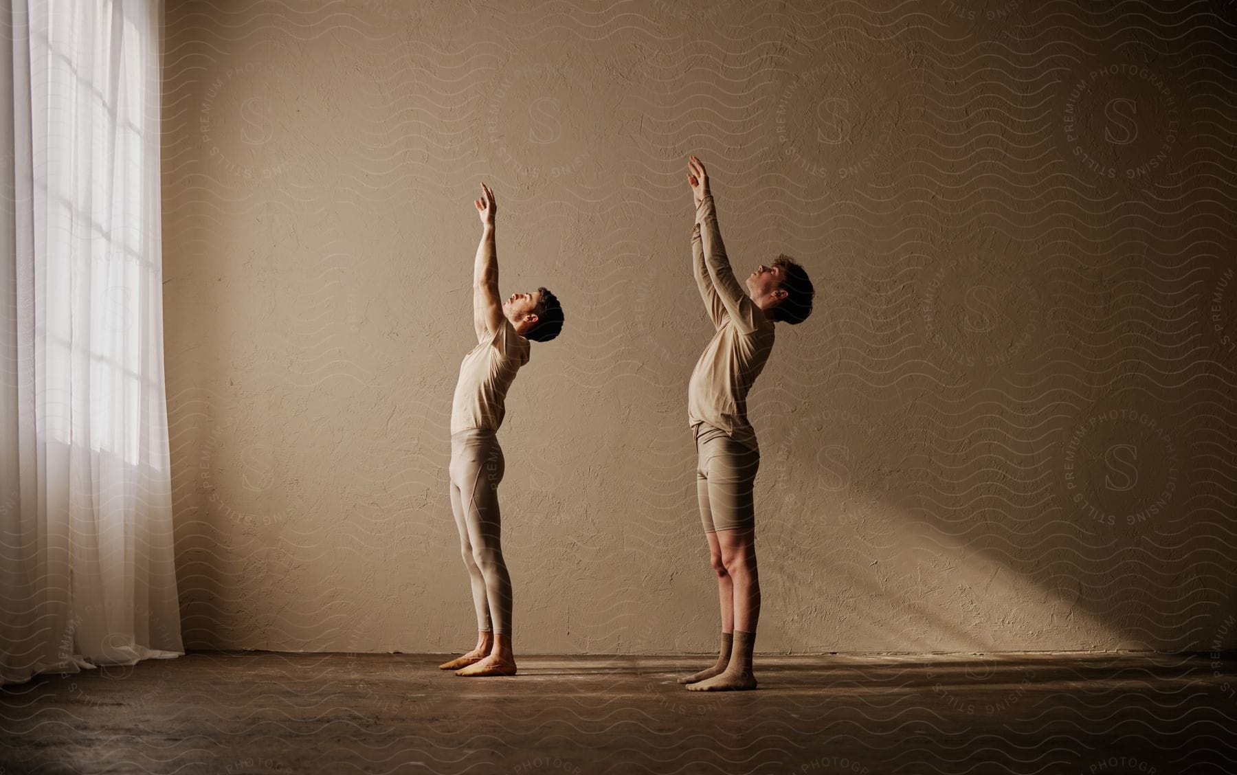 Stock photo of two young men with their hands up in a dance performance inside a room.