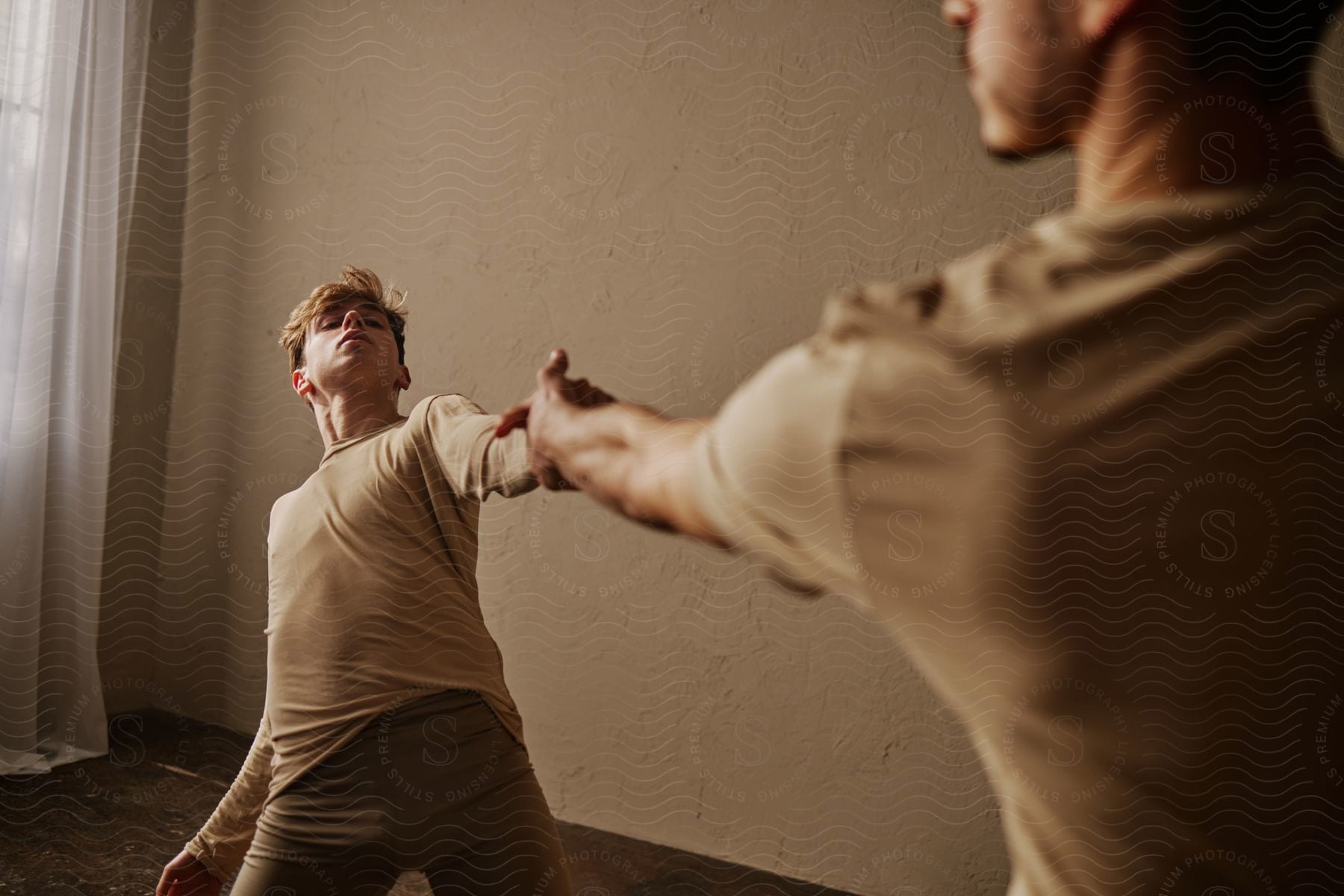 Stock photo of male dancers practice together in empty room.