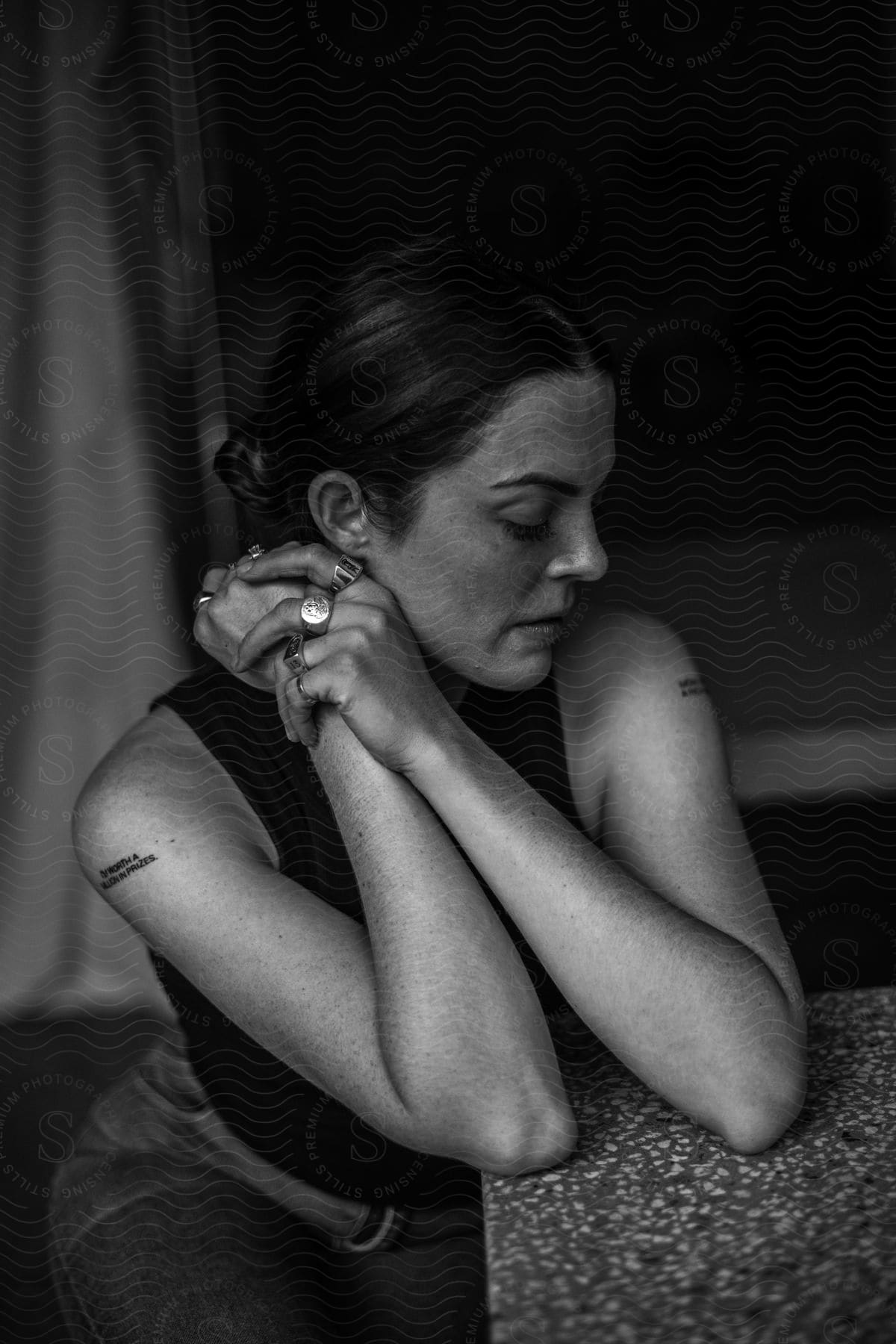 A woman clasps her hands and rests her elbows on a table.