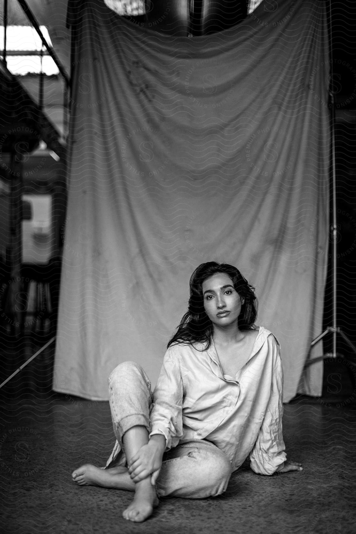 A woman is sitting on the floor with her hand on her leg as she looks ahead