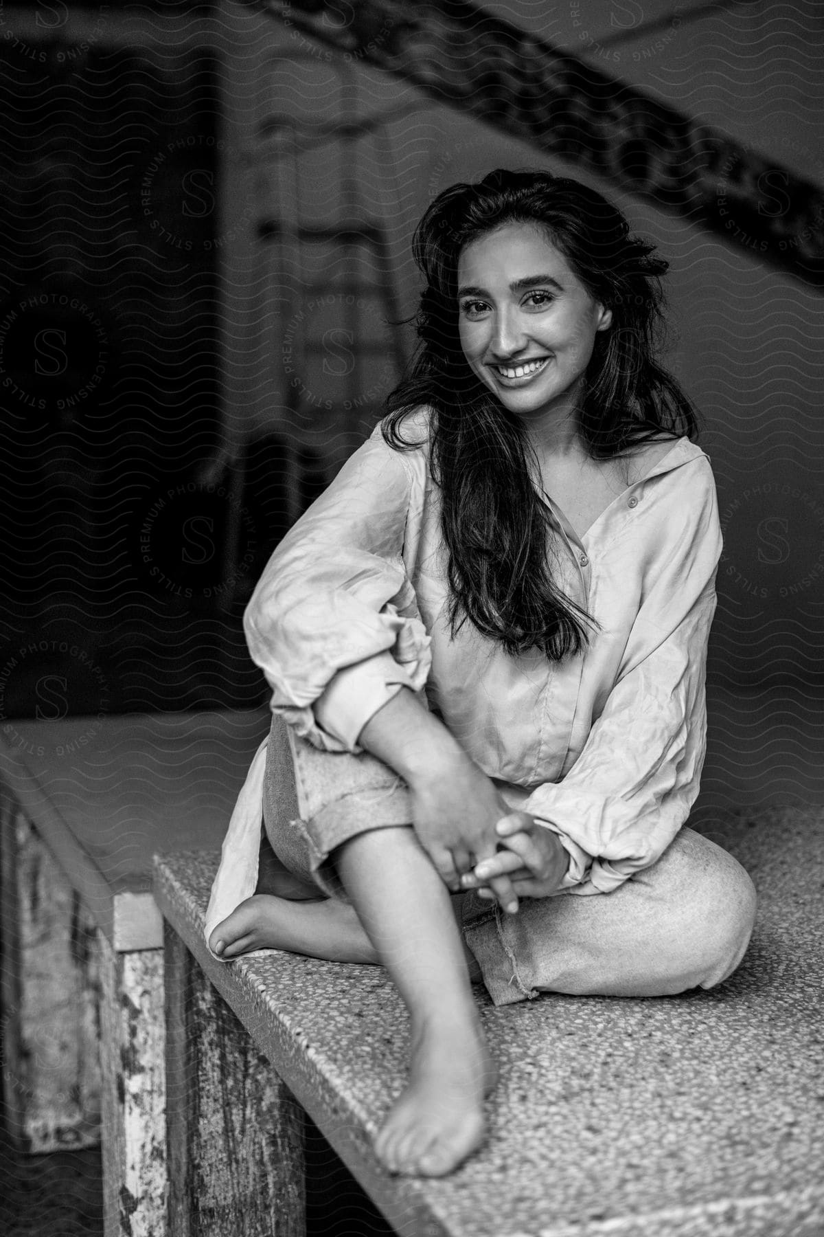 Woman smiles while sitting on platform in large room.