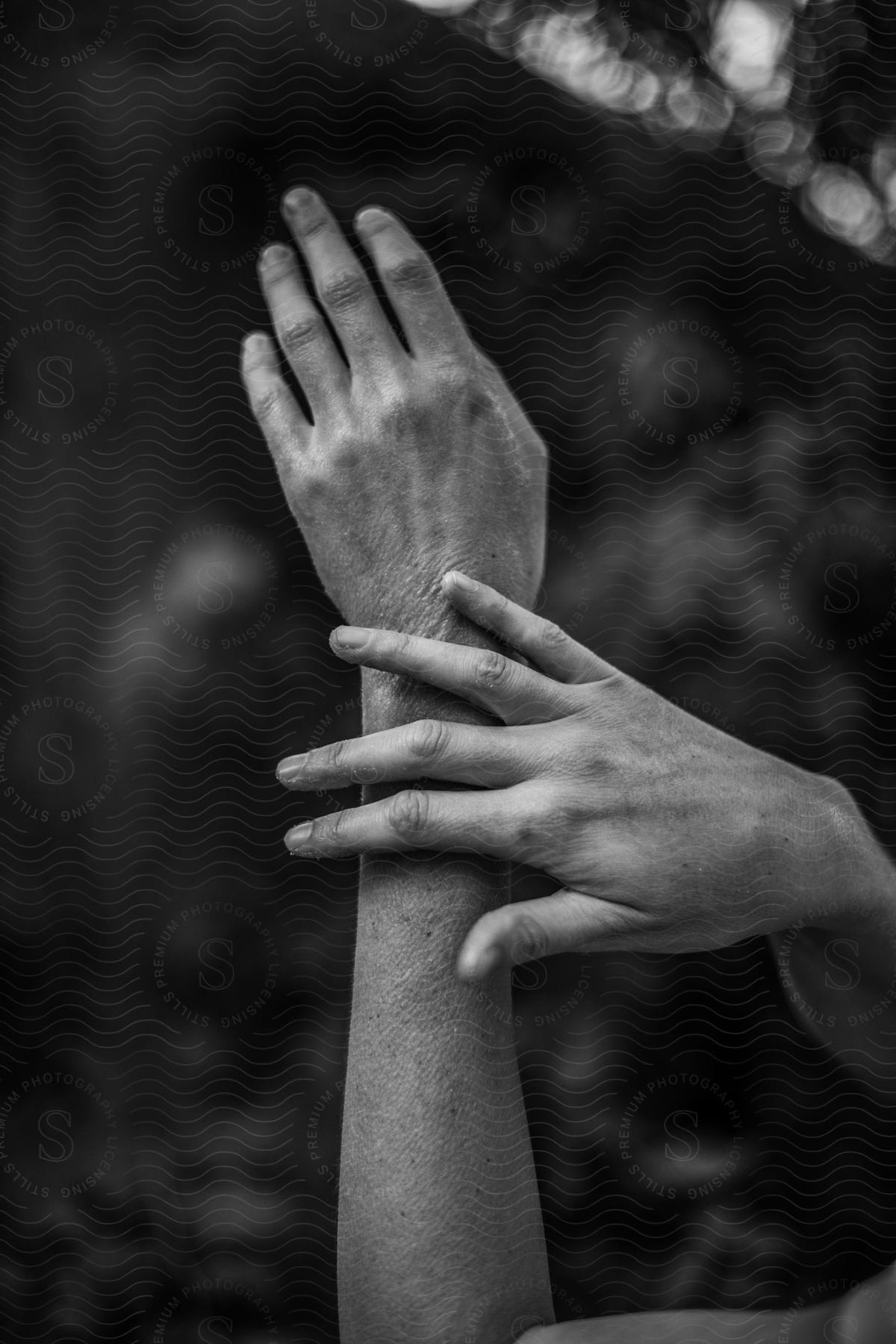 Two arms of a person with a hand touching an arm and everything is black and white.