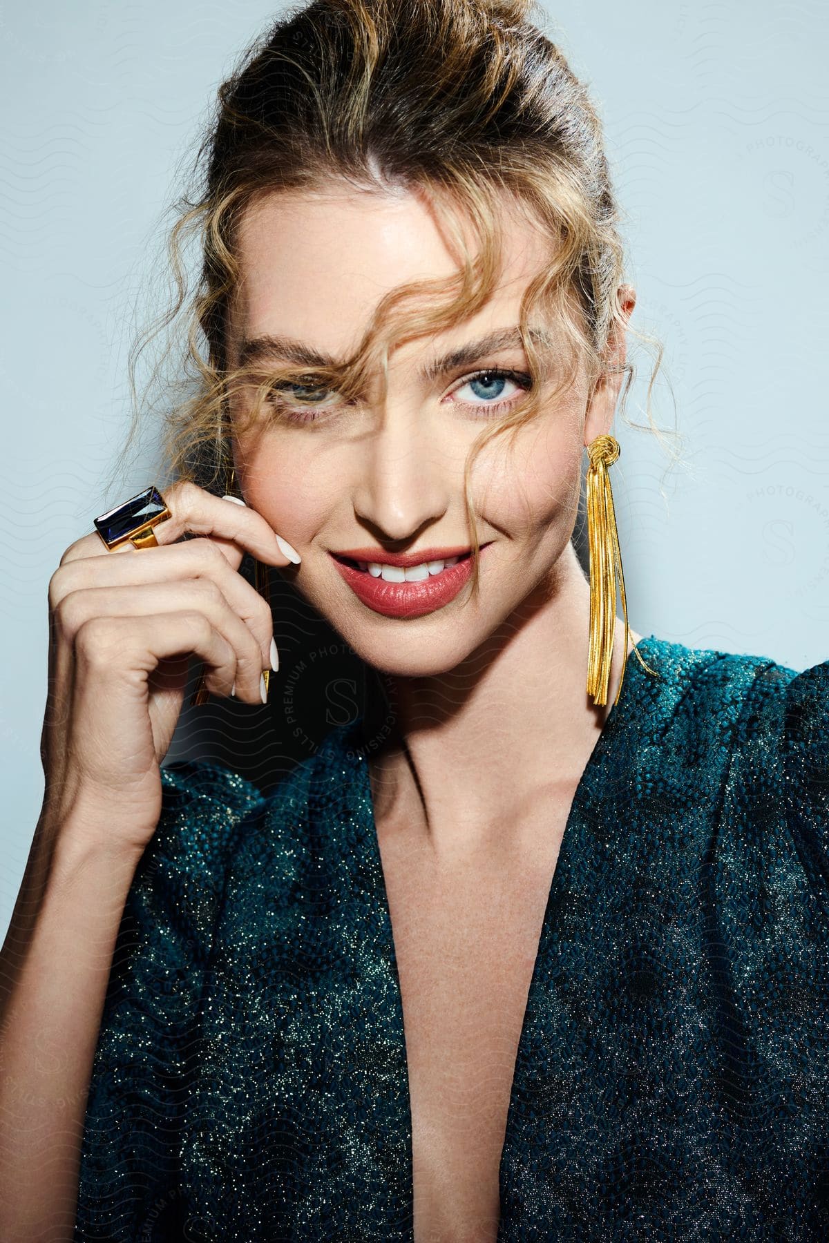 A beautiful woman with brown hair, wearing an emerald ring and blouse, laughs heartily