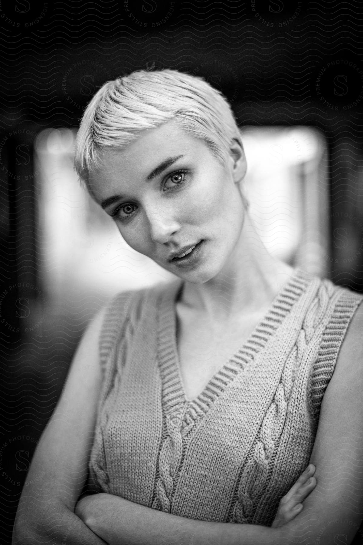 Portrait of a short-haired blonde woman with crossed arms in a black and white photo.