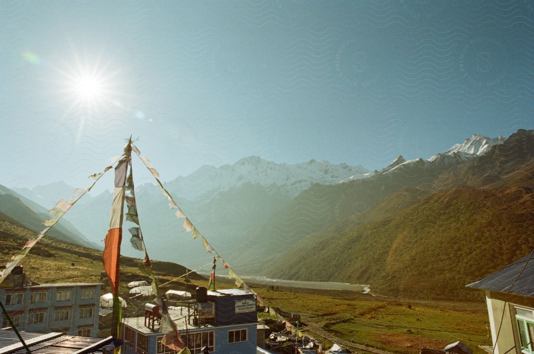 Two story buildings under prayer flags, snow capped mountains on horizon