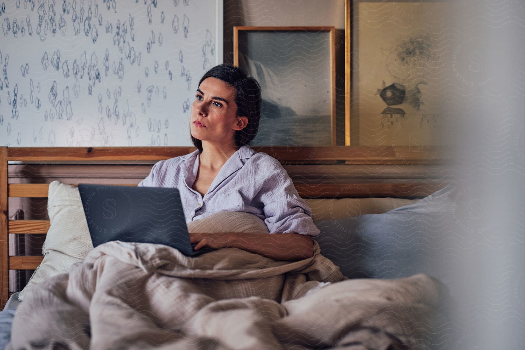 Woman lying in bed and holding a laptop on her lap.