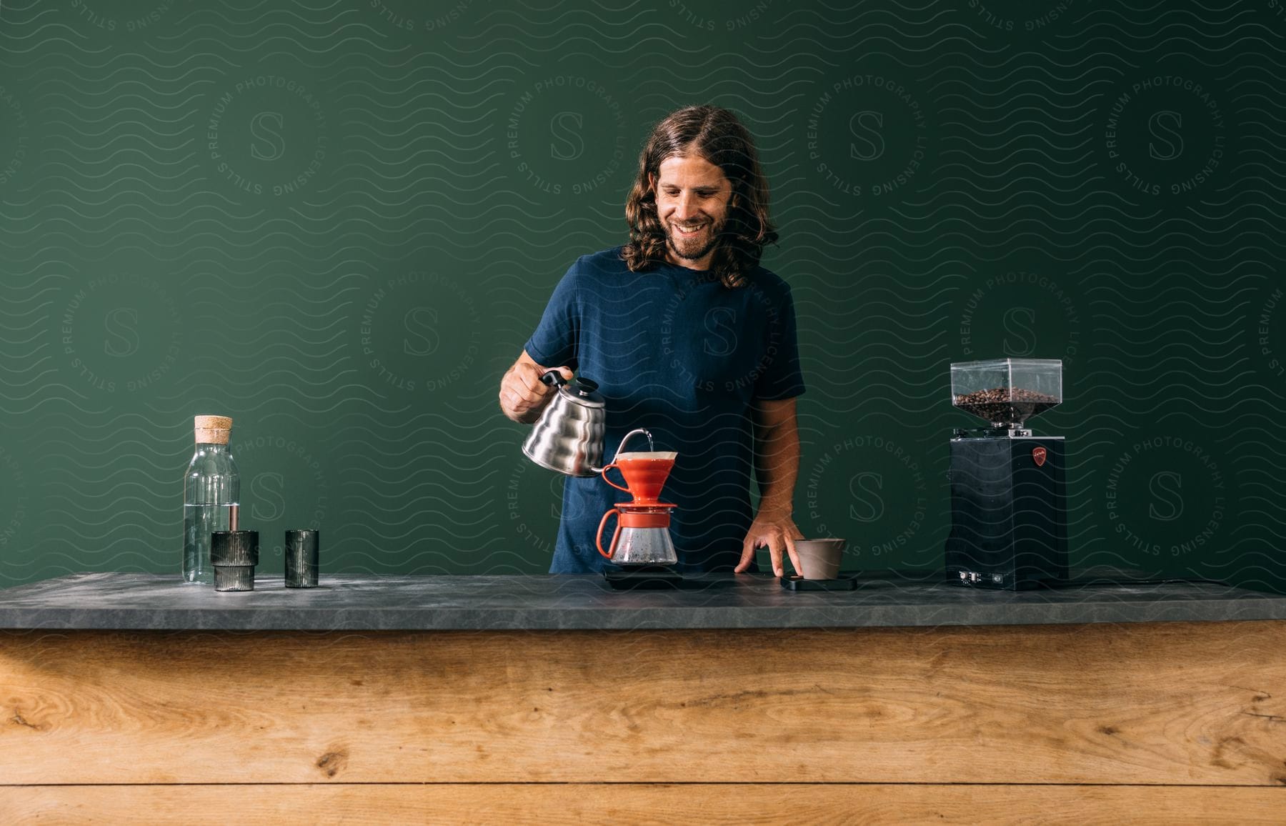 A man is making drip coffee by pouring water over the ground coffee beans.