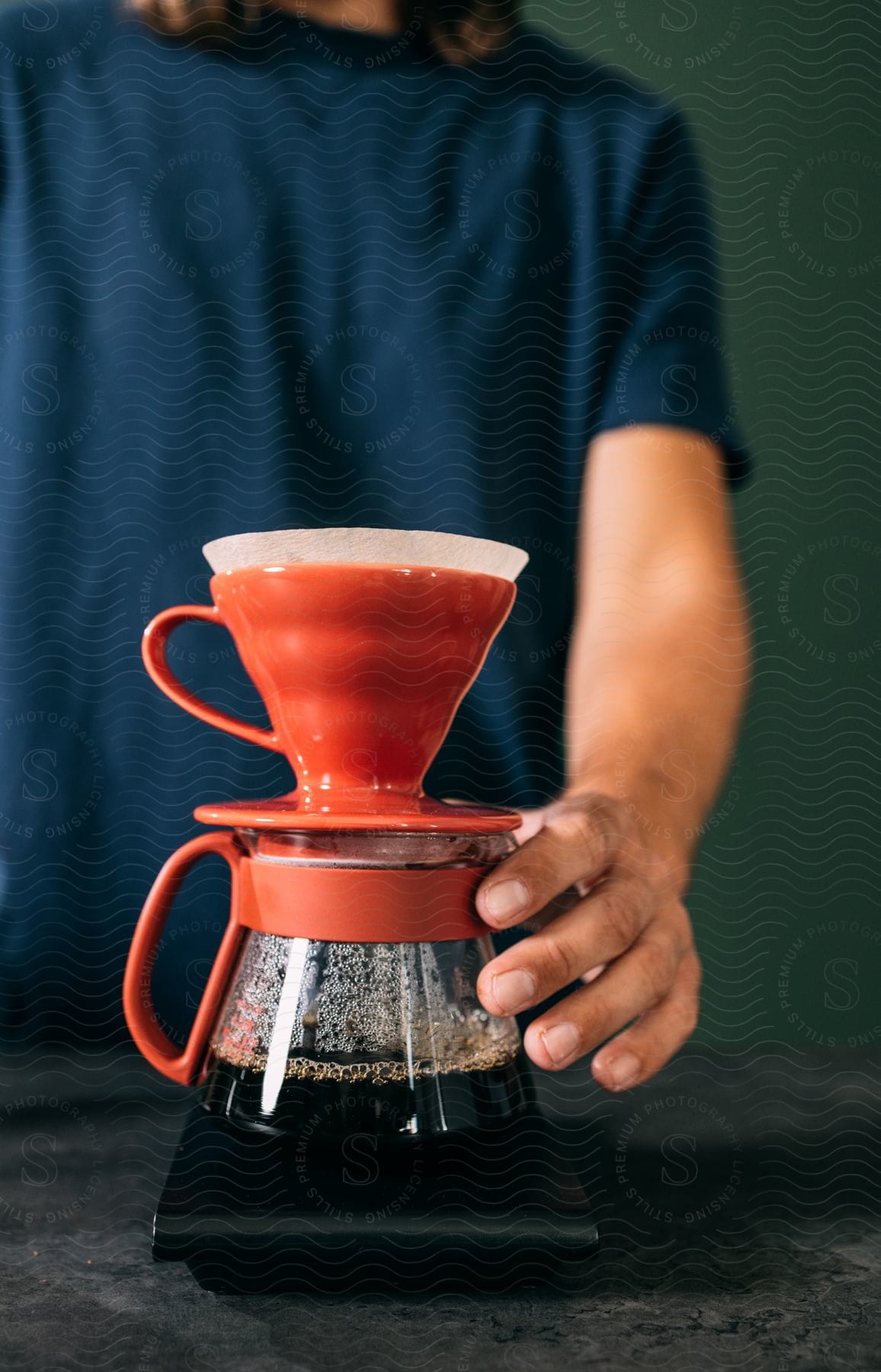 A man is holding his hand on a coffee pot as it brews