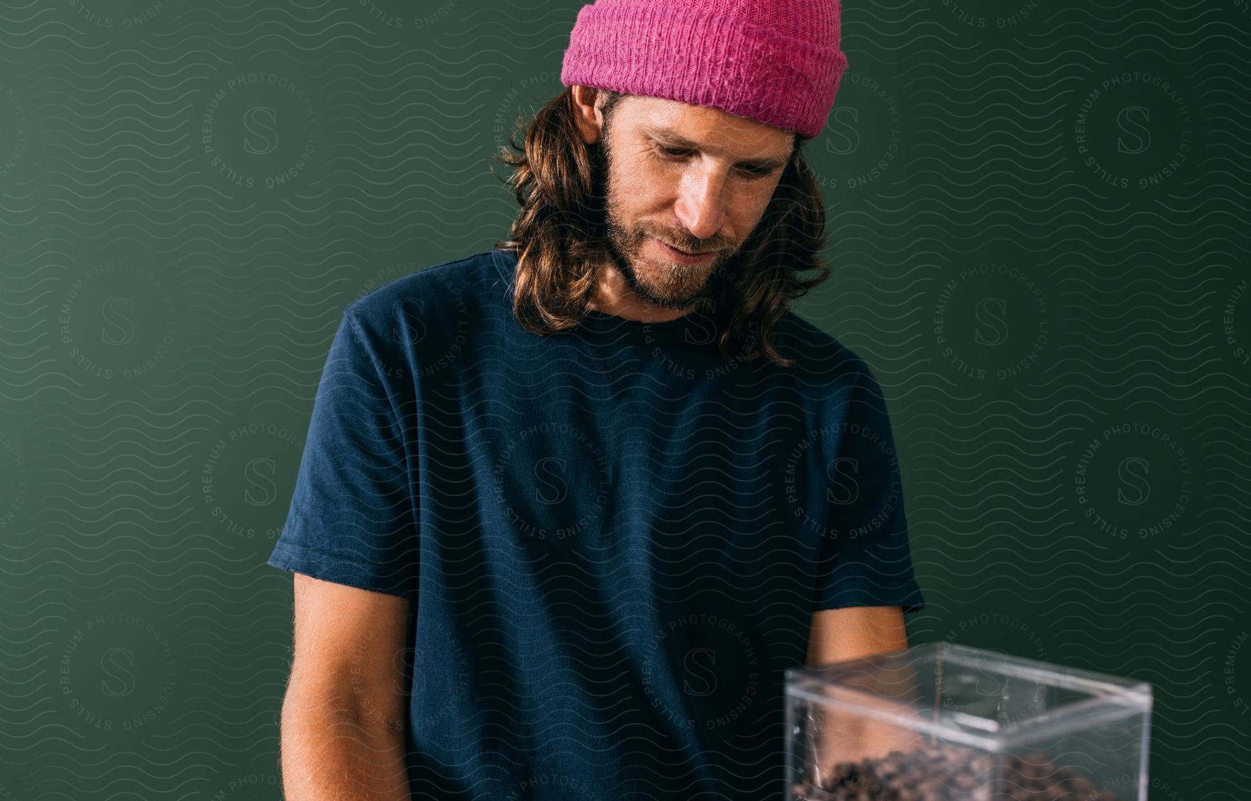 A man is standing in a room looking at a container of coffee beans