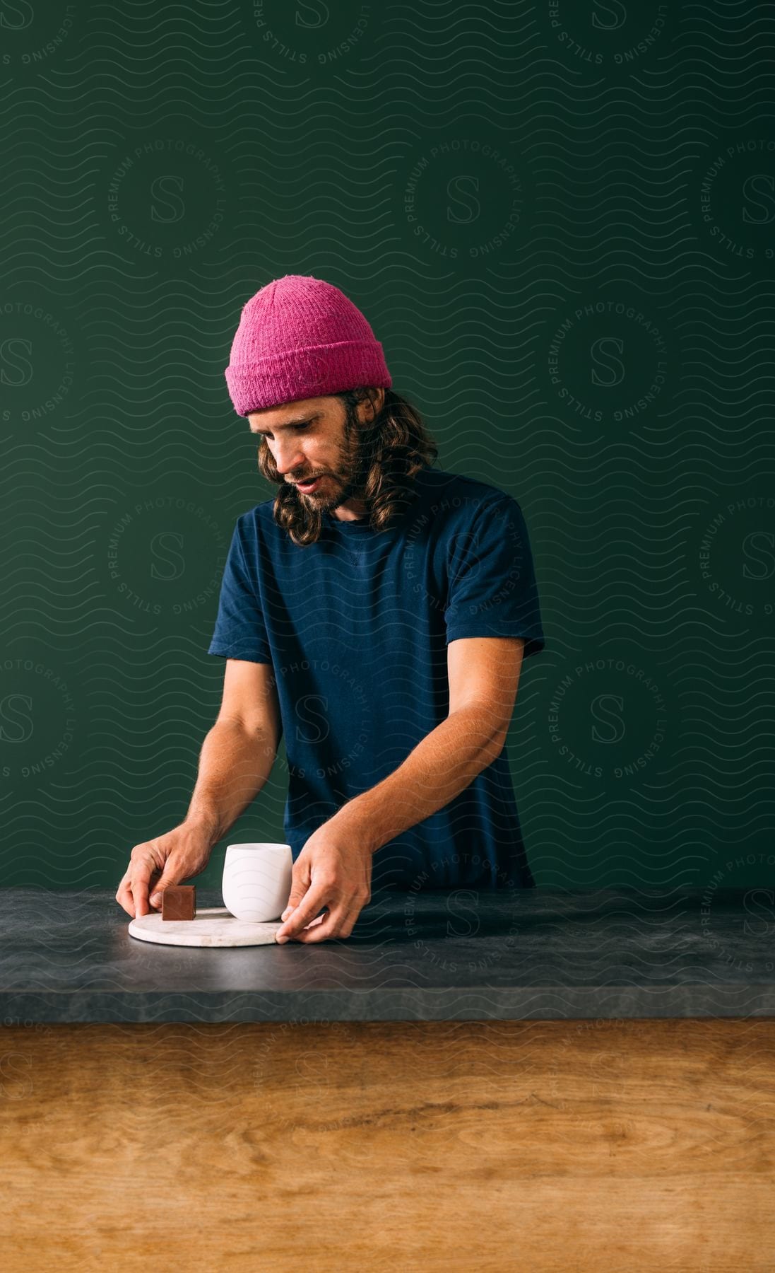 Man with long hair serves coffee over the counter