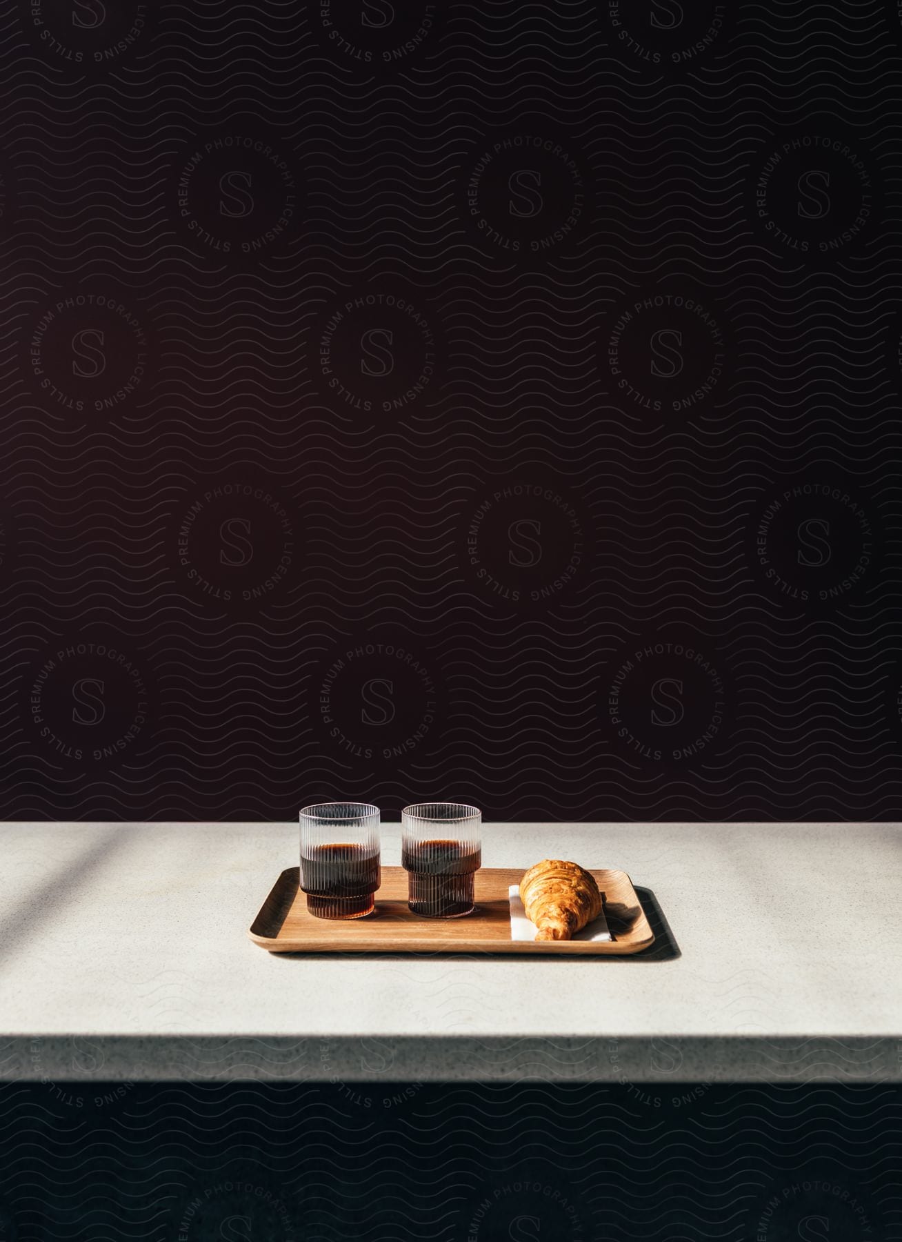 two glasses of coffee and a croissant on a wooden tray