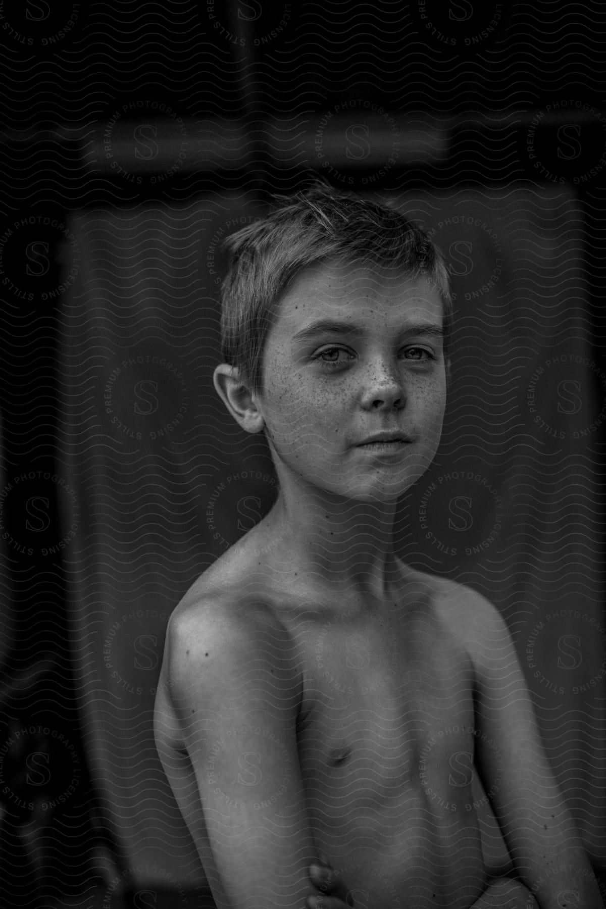 young boy sits with both arms wrapped around the waist