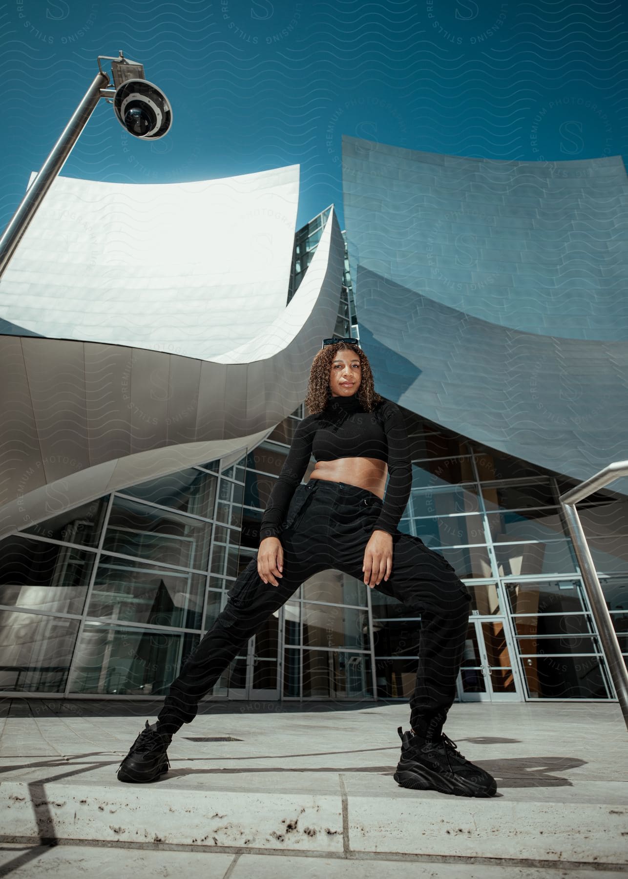 Woman poses in front of building with curved sloping roof.