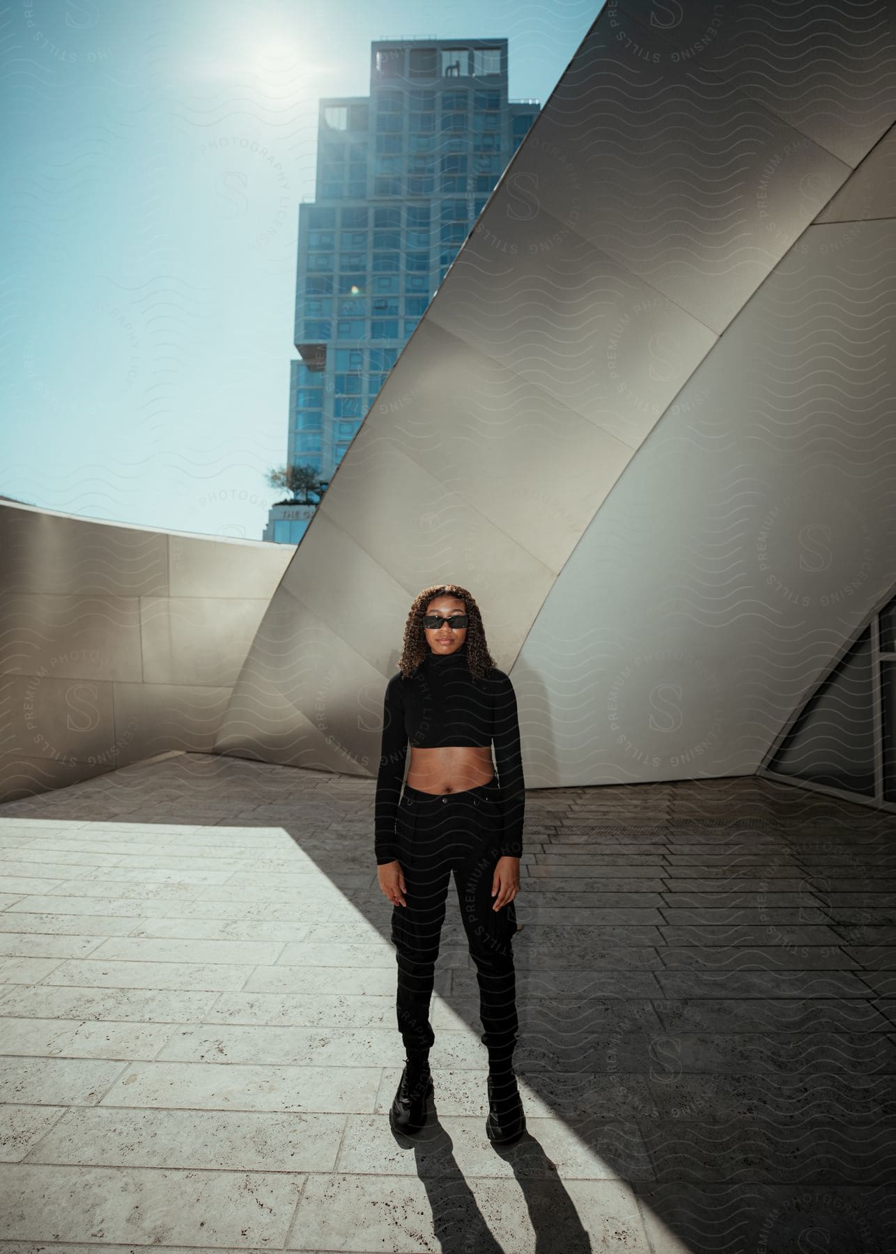 Woman in an outdoor area of the building posing in an all-black outfit.