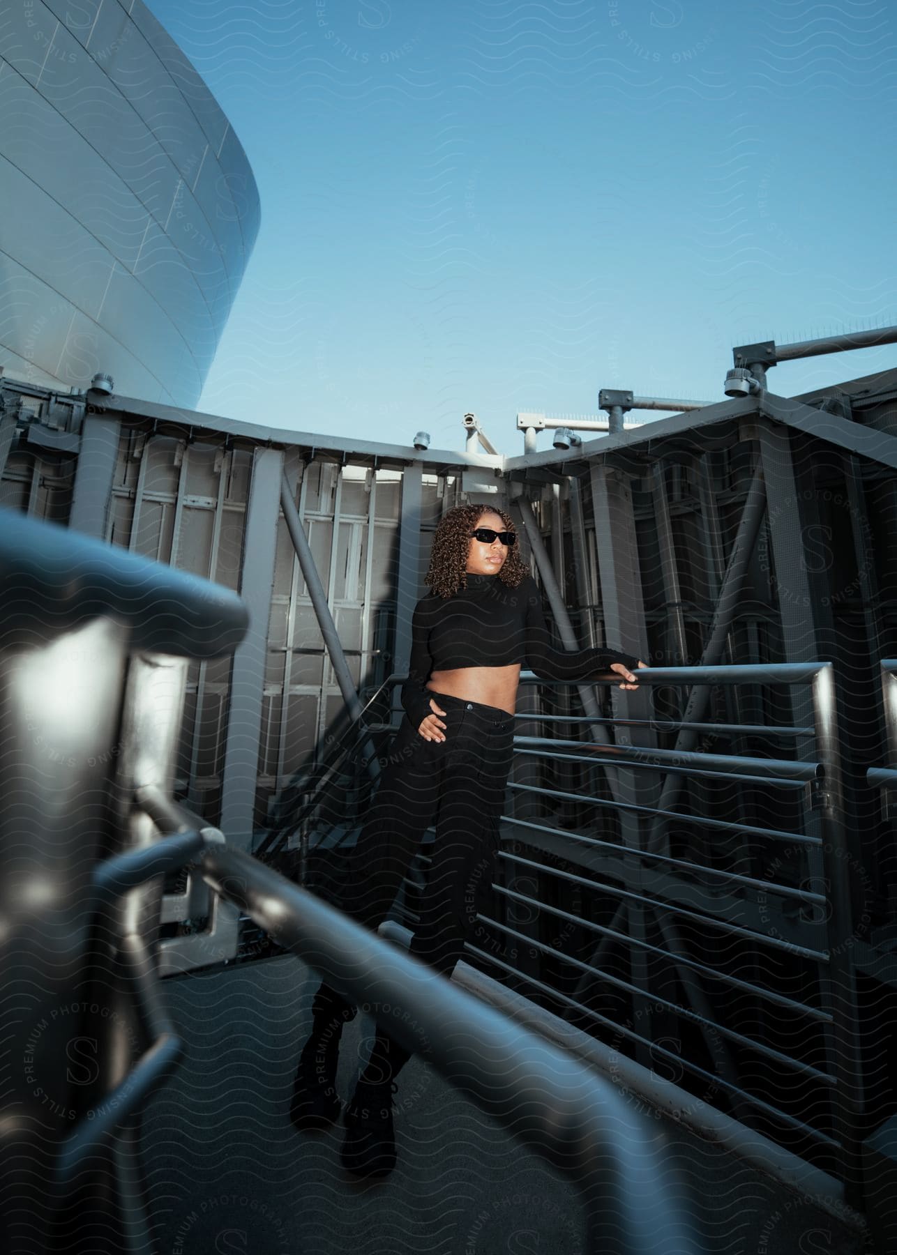 Woman leaning on a railing and modeling in an all-black outfit.