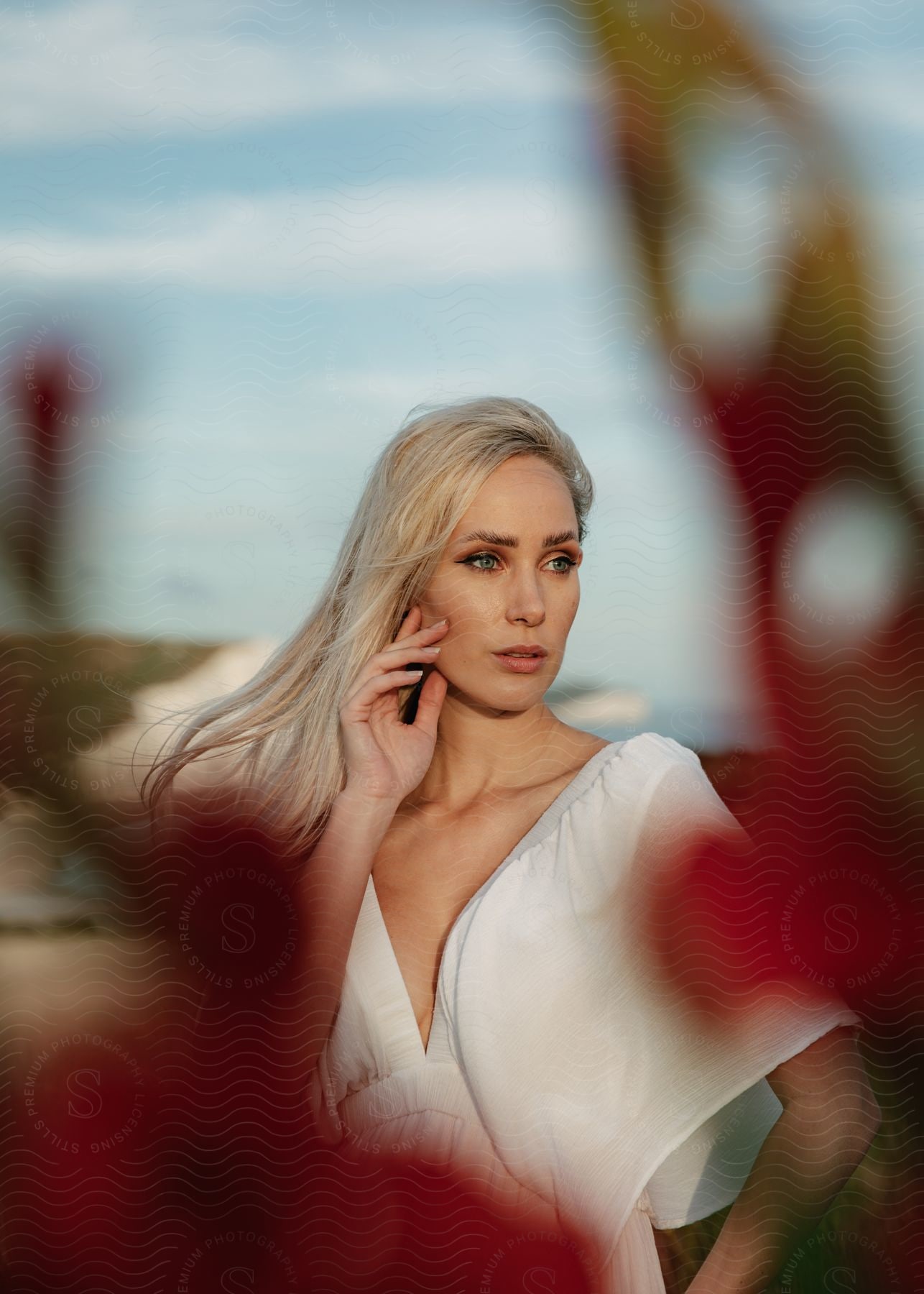 Woman wears white outfit with white cliff in the background.