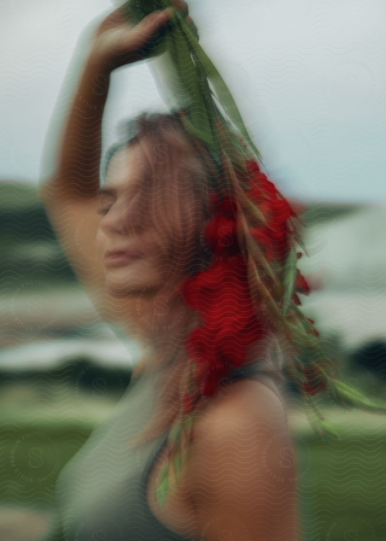 A woman is standing outside holding a bouquet of flowers over her head