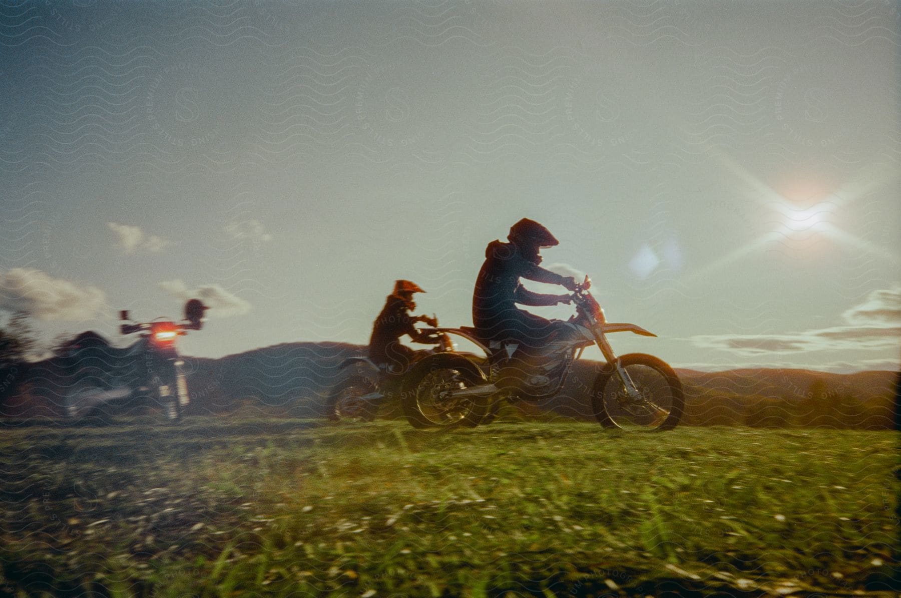 Two people on motorcycles in nature on a sunny day.