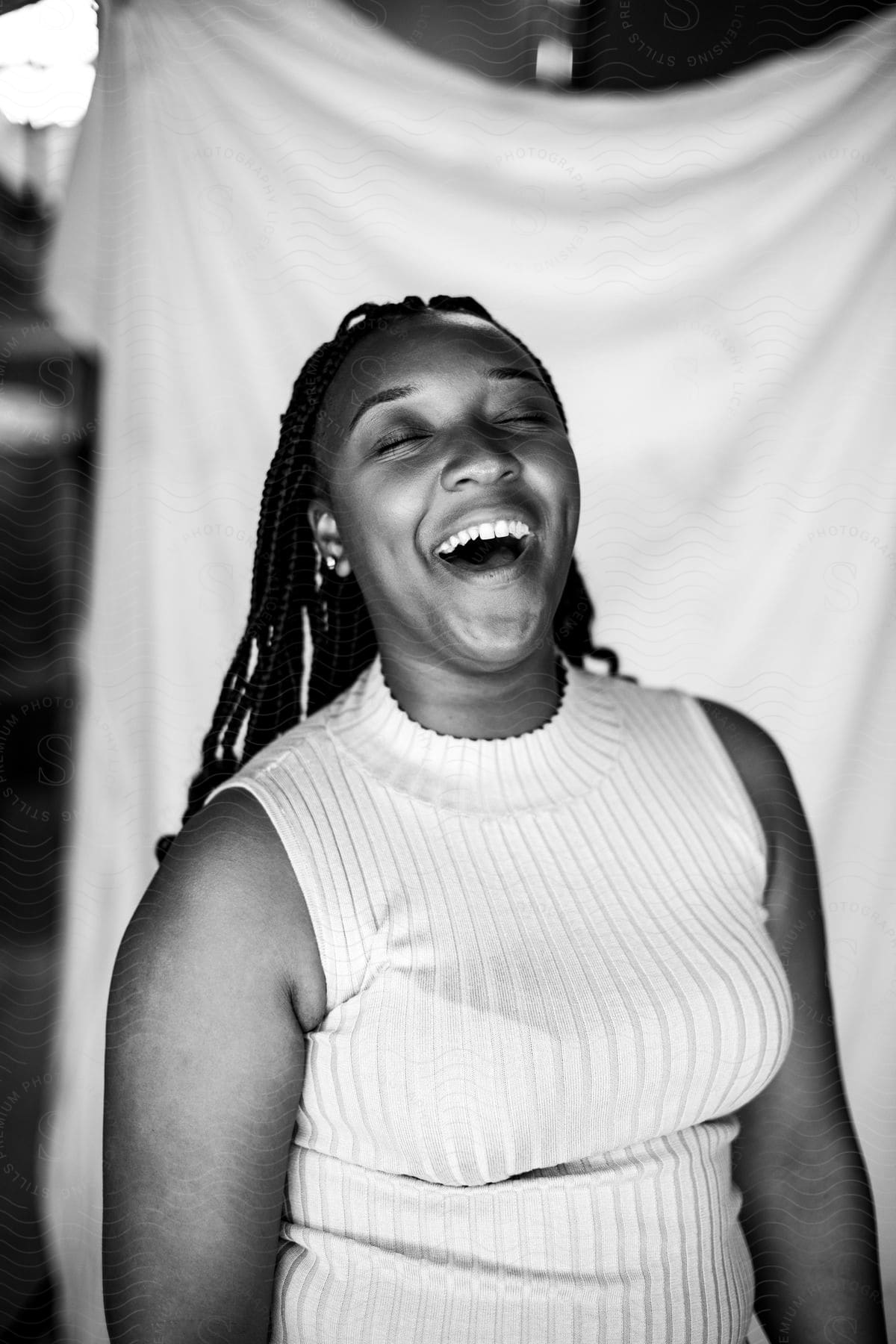 A young, black woman poses while laughing with her head tilted up.