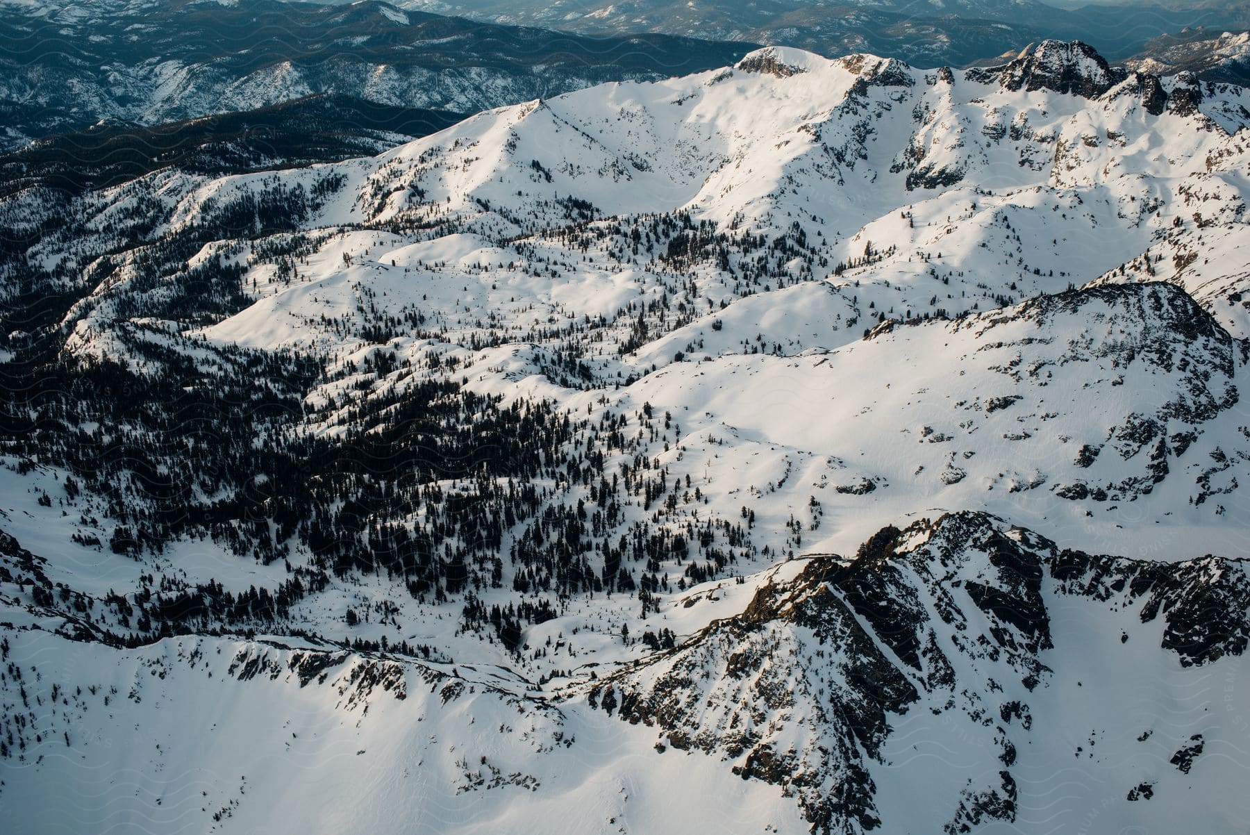 Aerial panorama of snow-covered mountains and forests.