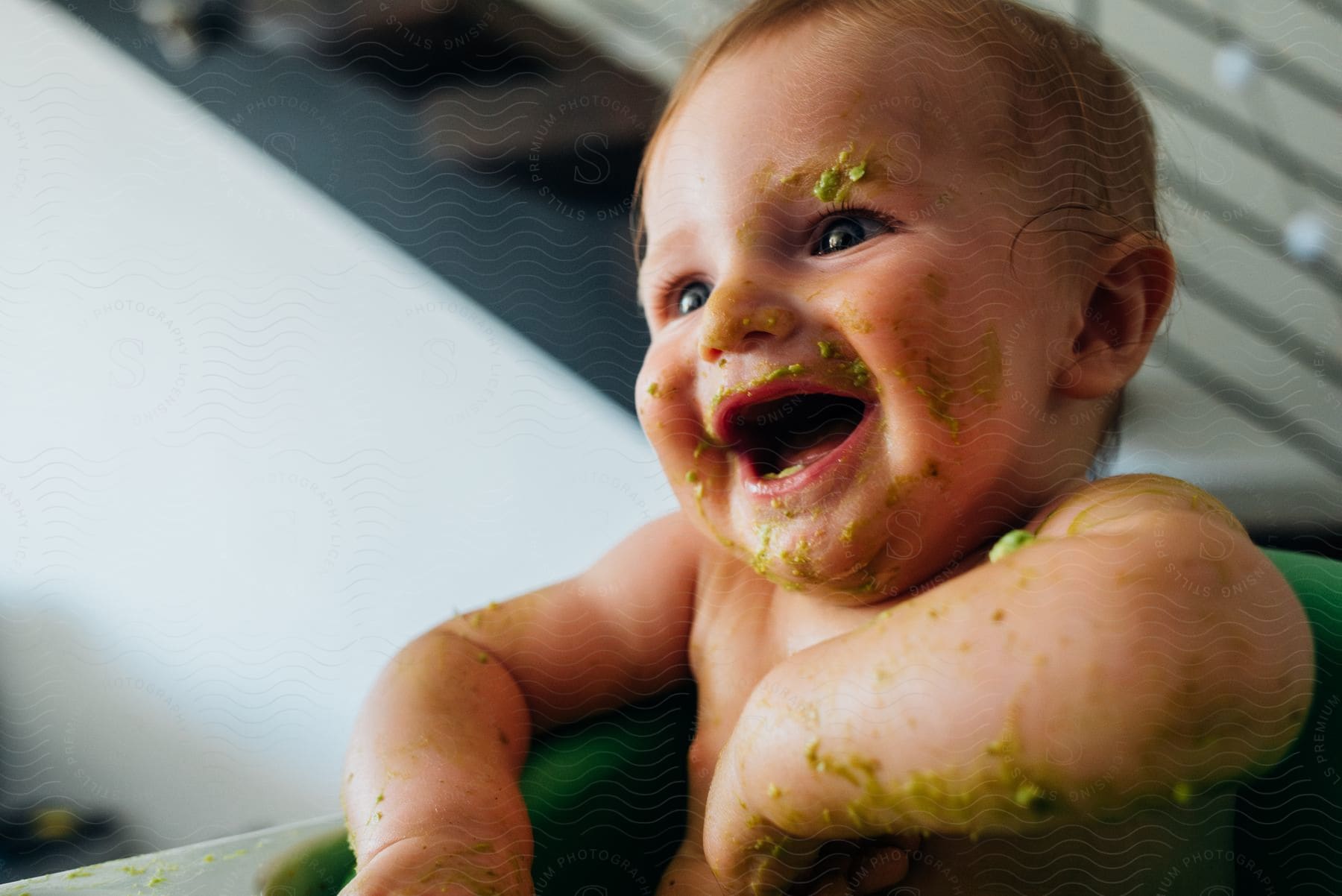 Portrait of a baby with green goo on the body and smiling.