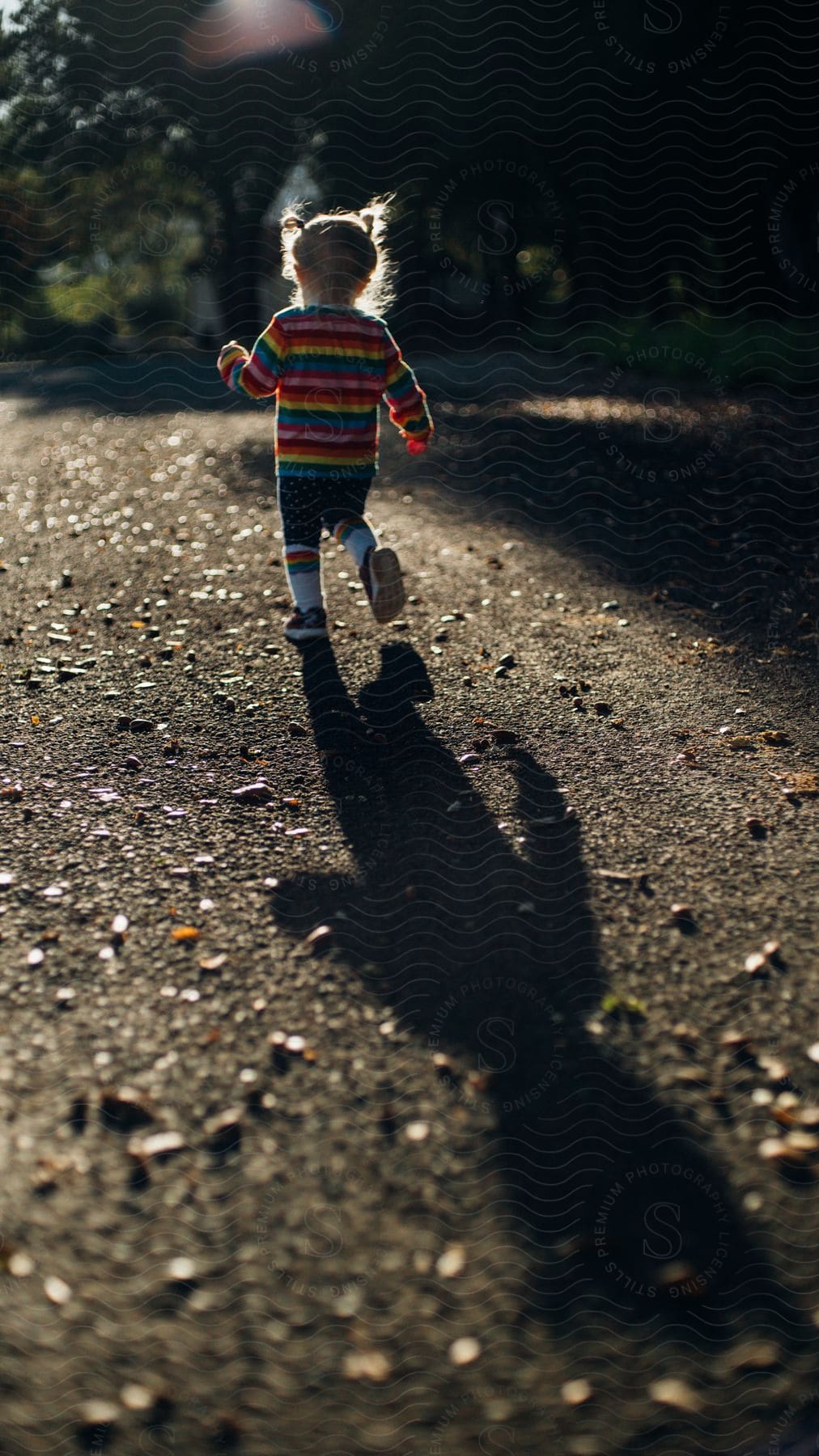 A child running around in a forest on a sunny day.