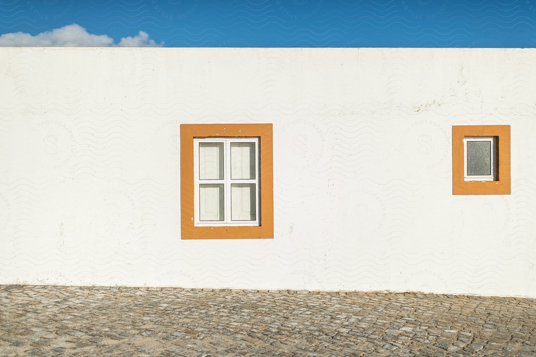 A white wall with two rectangular windows framed in orange.