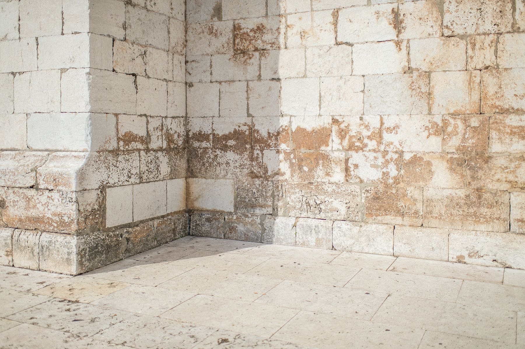 a corner of a building with a weathered brick wall.