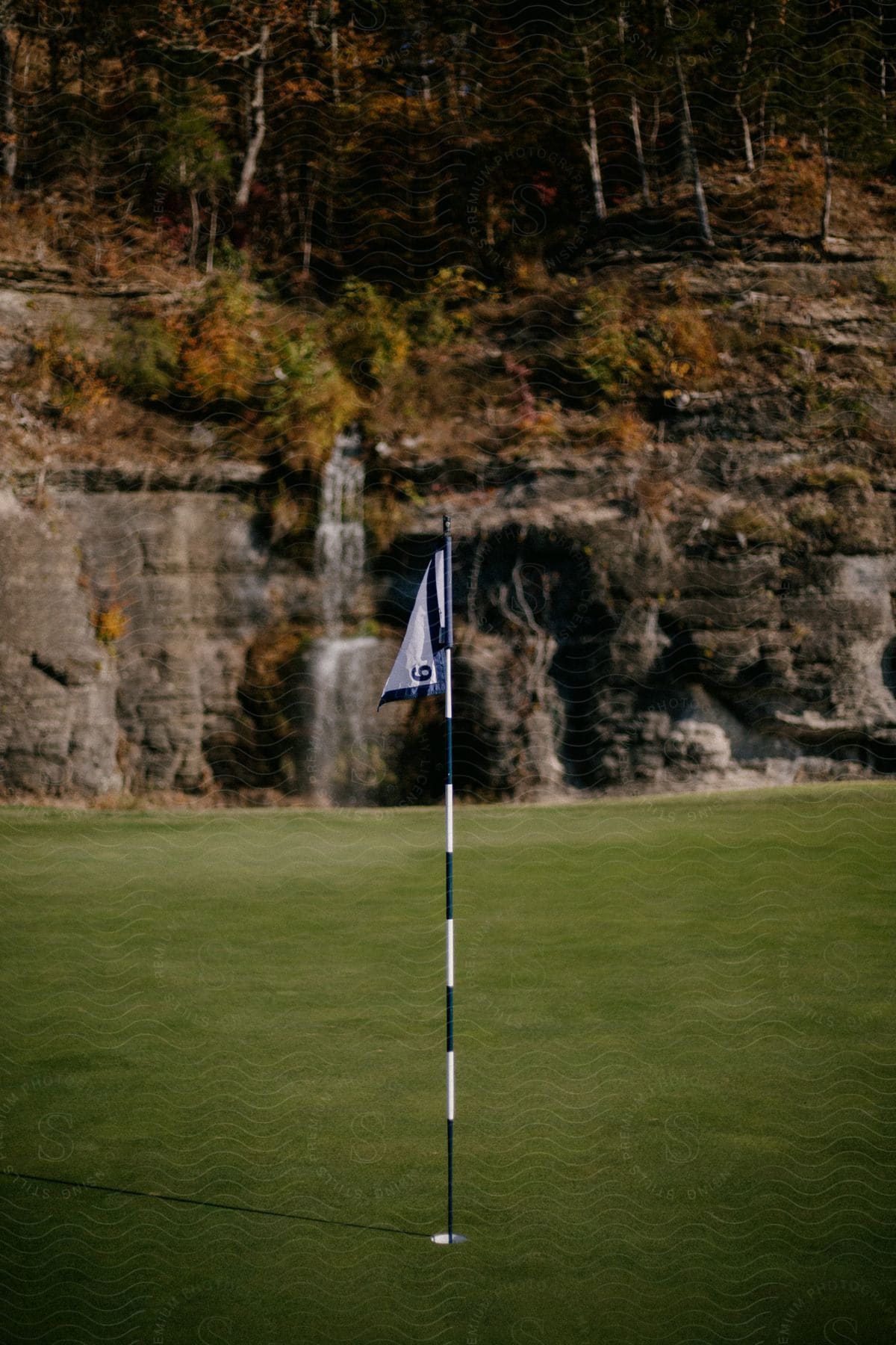 A flag on a golf course with a mountain in the background.