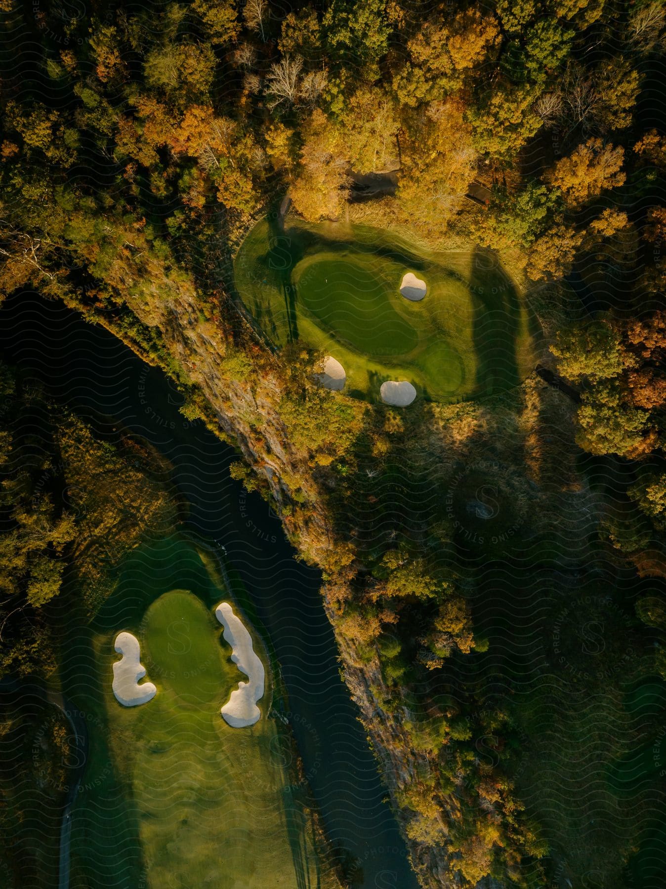 Stock photo of aerial view of a river running between golf courses with trees in fall colors
