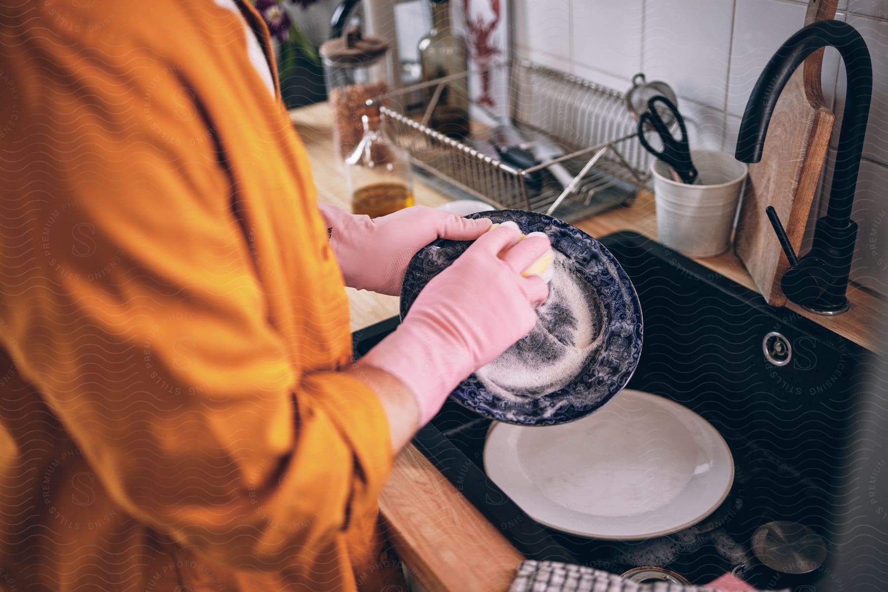 a man wearing a glove is in the kitchen washing the dishes