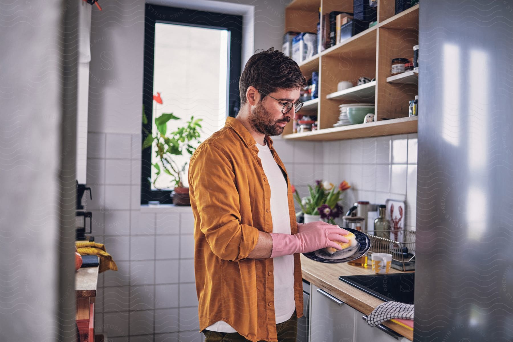 Man in a kitchen washing a dish.