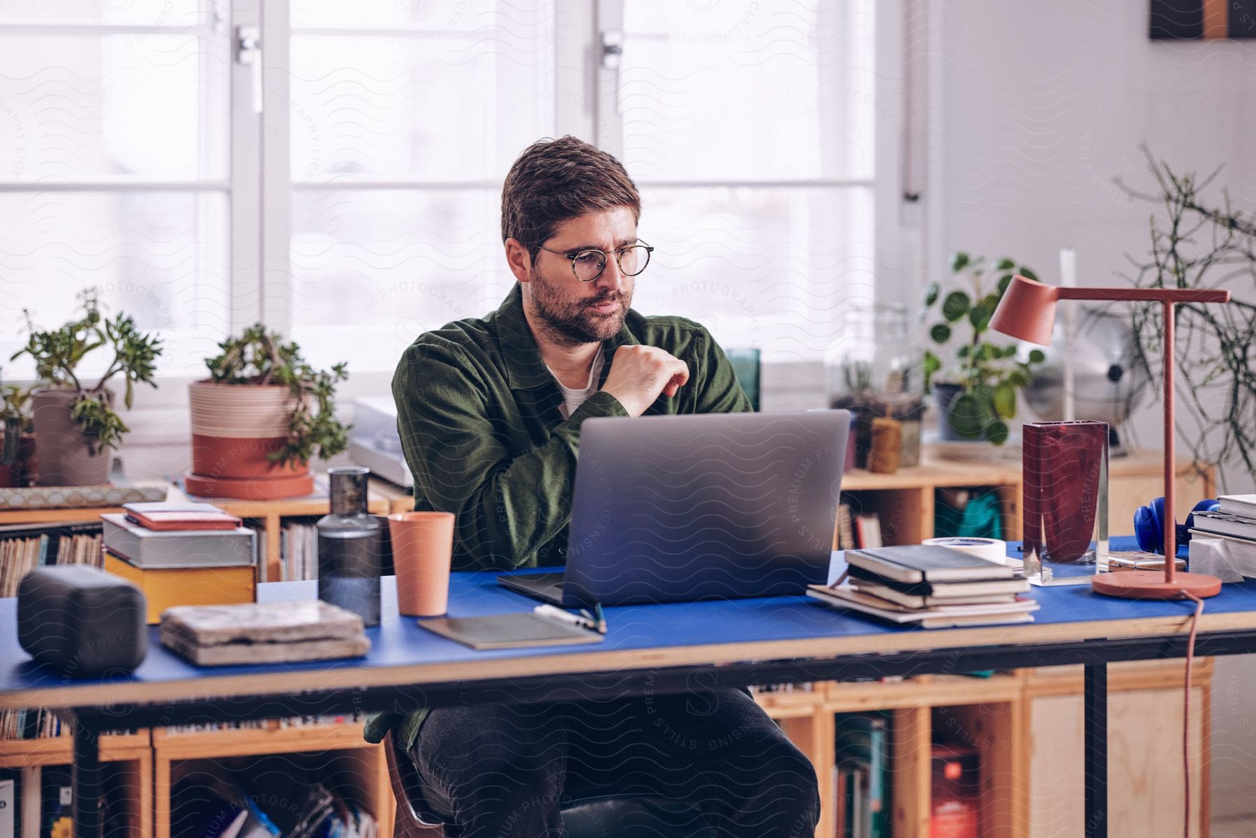 A man is sitting at a desk looking at a laptop computer