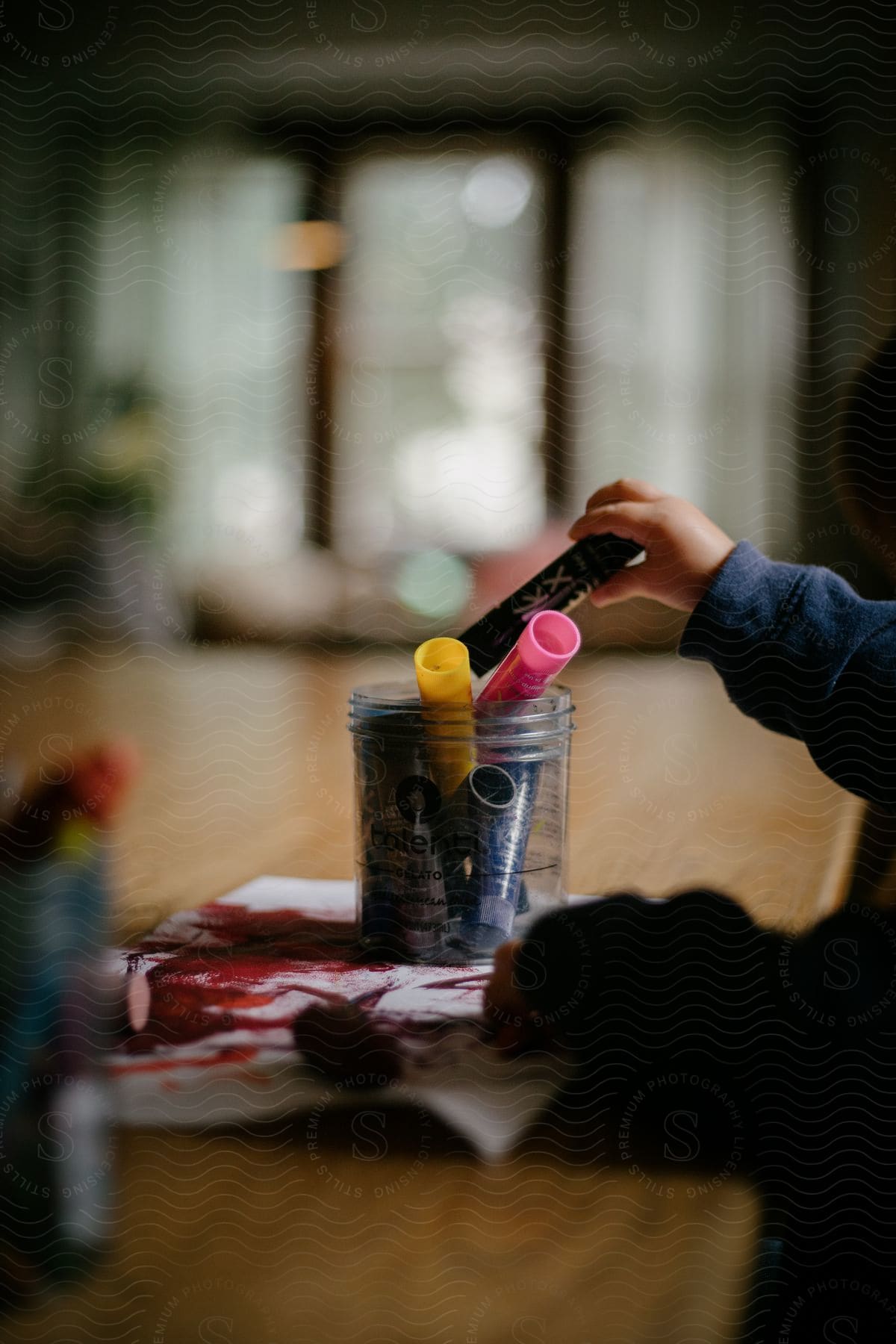 a child sitting at a desk puts a Kwik Stix in a jar