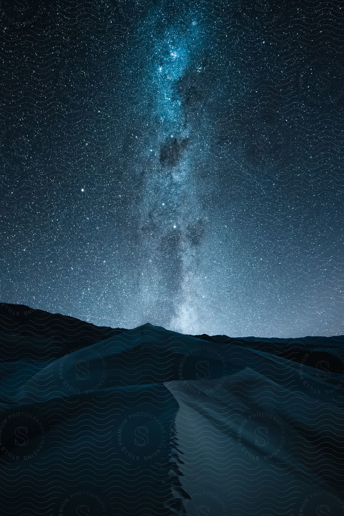 A view of the milky way and other stars over a landscape.