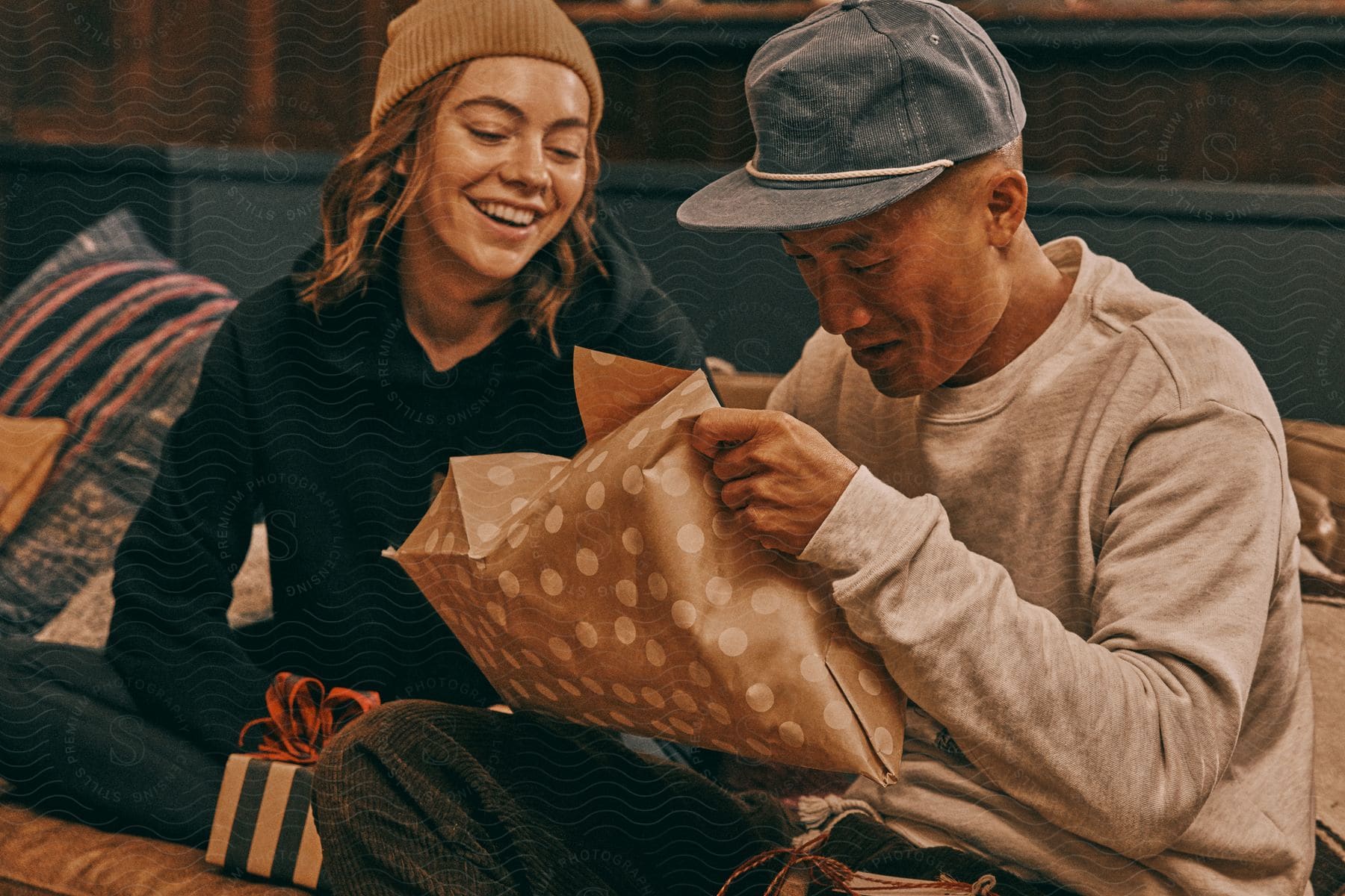 Friends sitting on the sofa exchanging Christmas gifts.