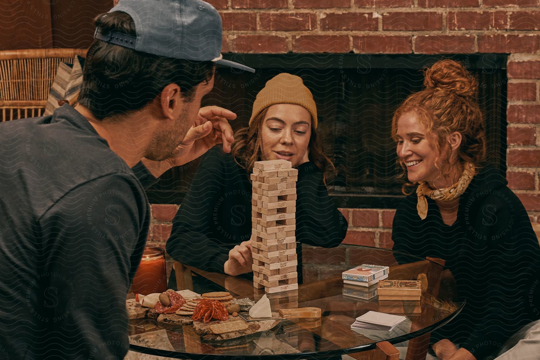 Three young adults sitting at a table, smiling and playing a game.